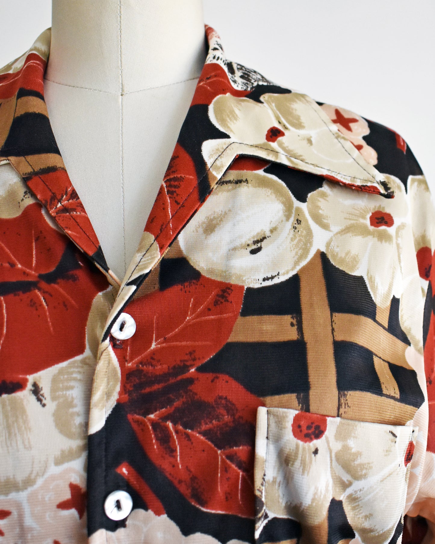 close up of the collar and print of a a vintage 1970s fruit and florals disco shirt on a dress form