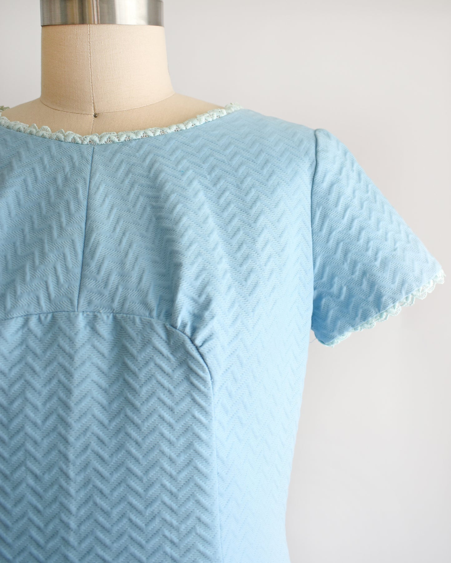 Close up of the bodice that shows the textured chevron and ribbed fabric, along with lace trim