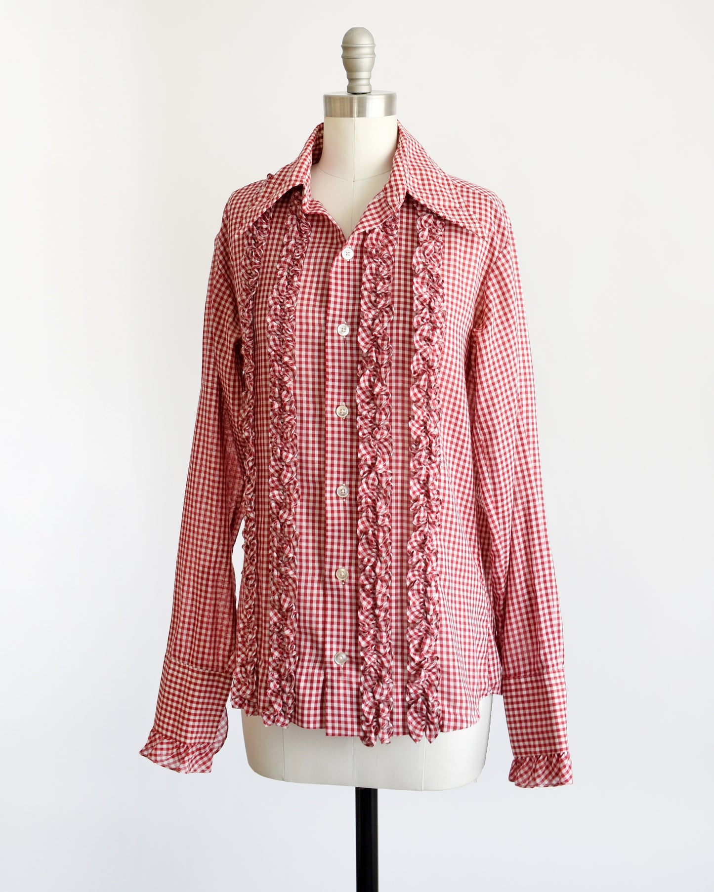 Side front view of a vintage 1970s red and white gingham check with plastic buttons down the front and two on the ruffled cuffs