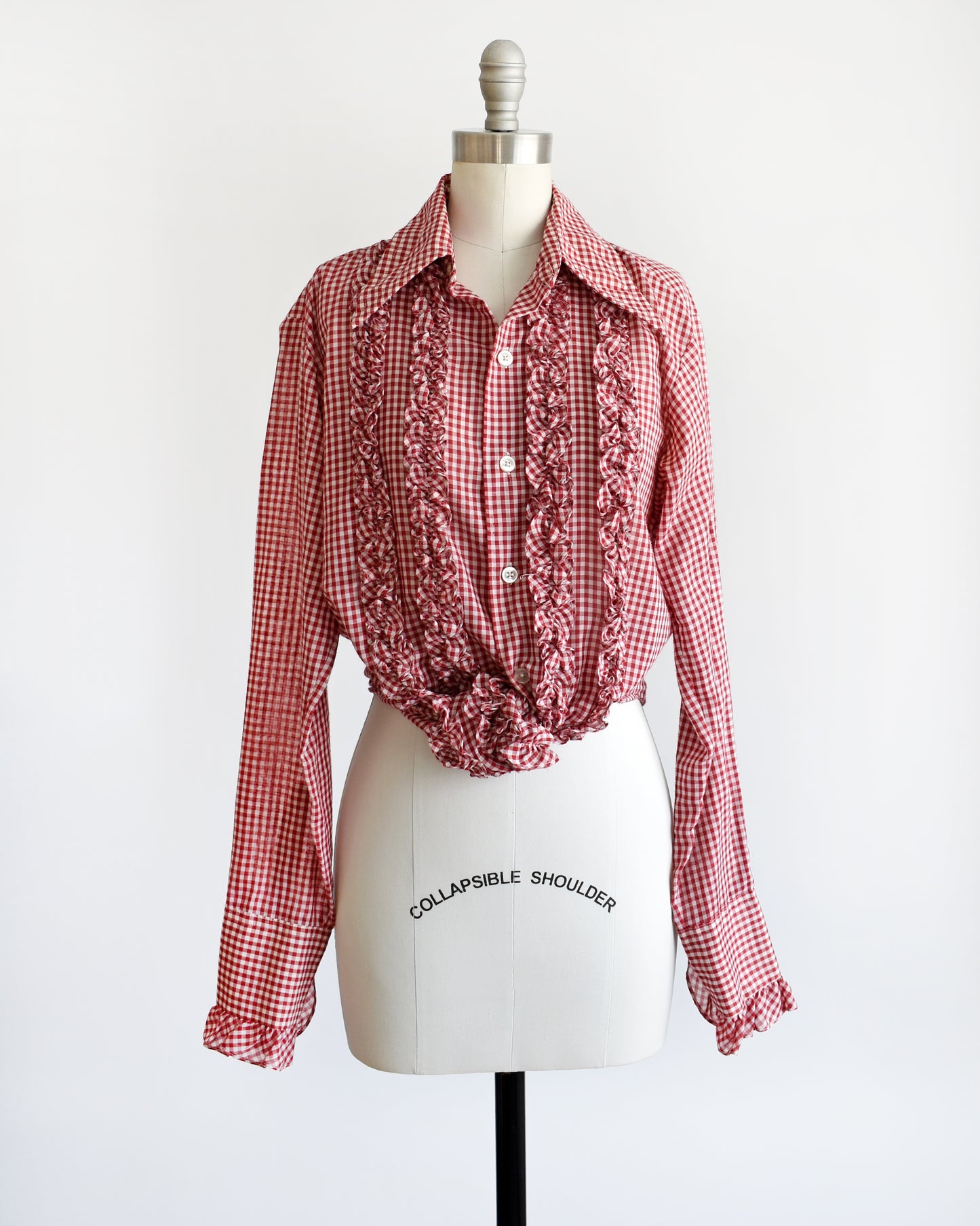 A vintage 1970s red and white gingham check with plastic buttons down the front and two on the ruffled cuffs. The blouse is tied int he front giving it a cropped look