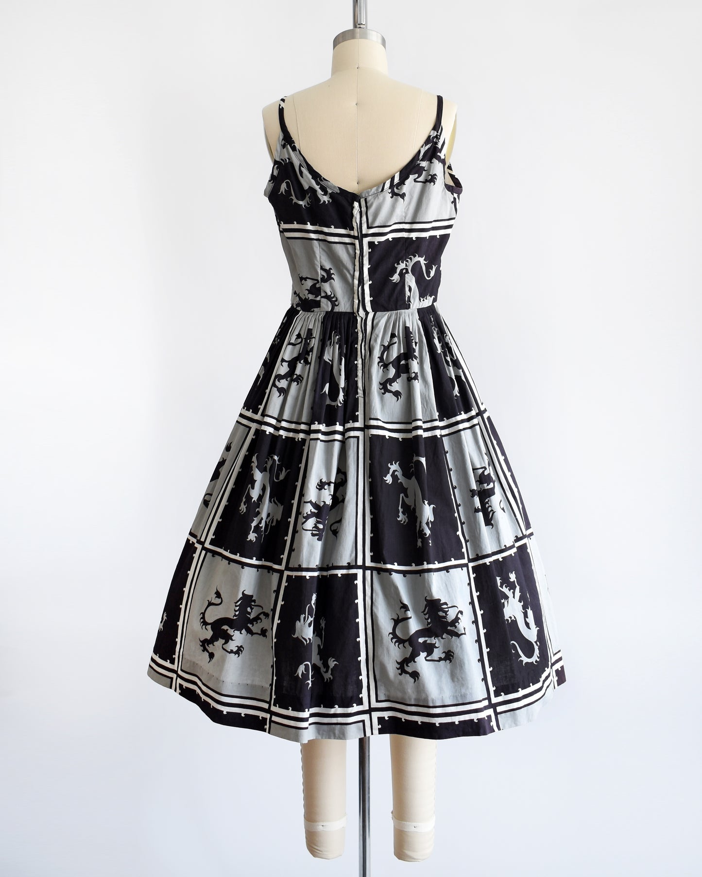 Back of a vintage 1950s that has a black and light gray checkered pattern with a Scottish lion in each center, framed by black and white stripes.