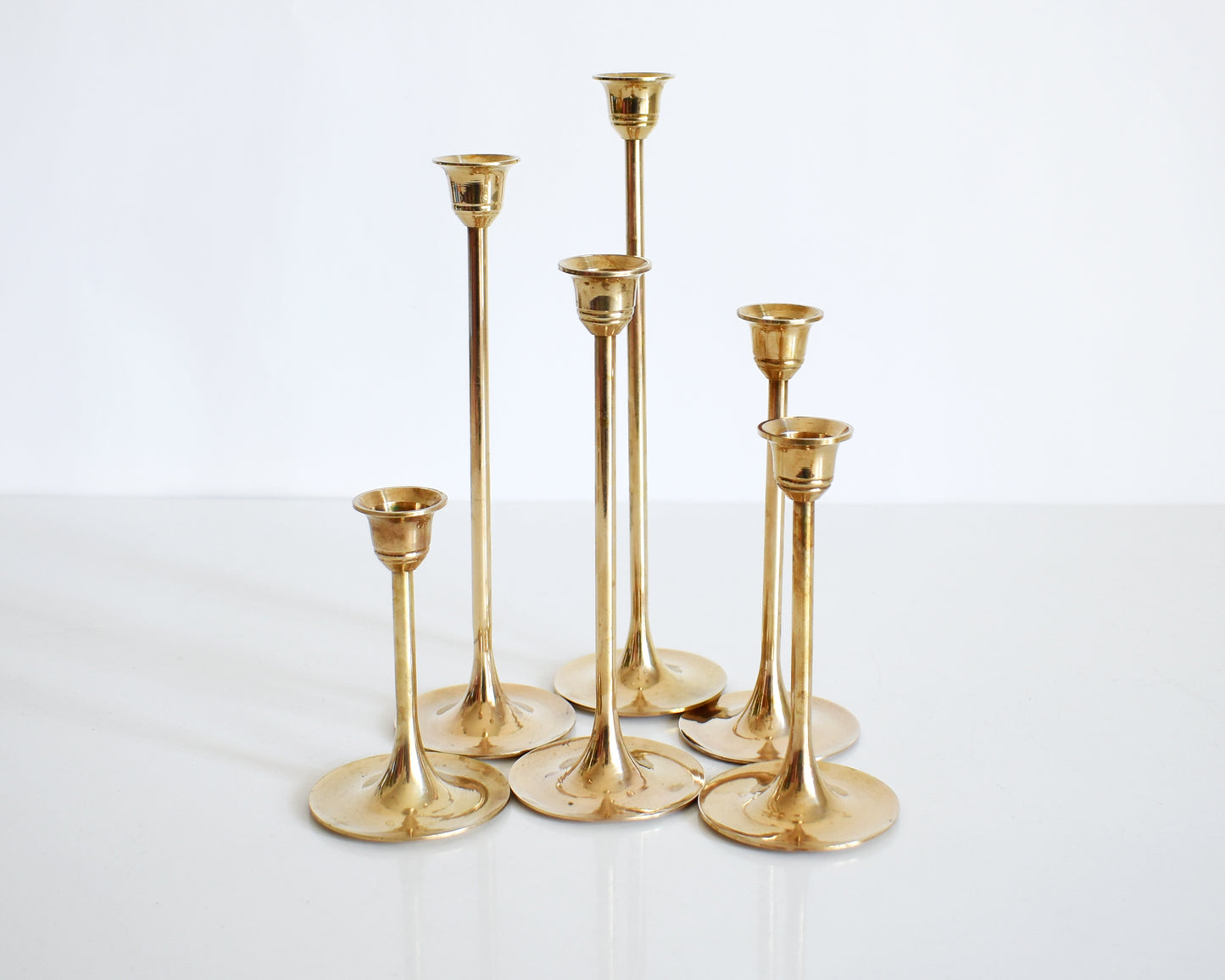 A vintage of six of different vintage brass graduated candlesticks in a group.