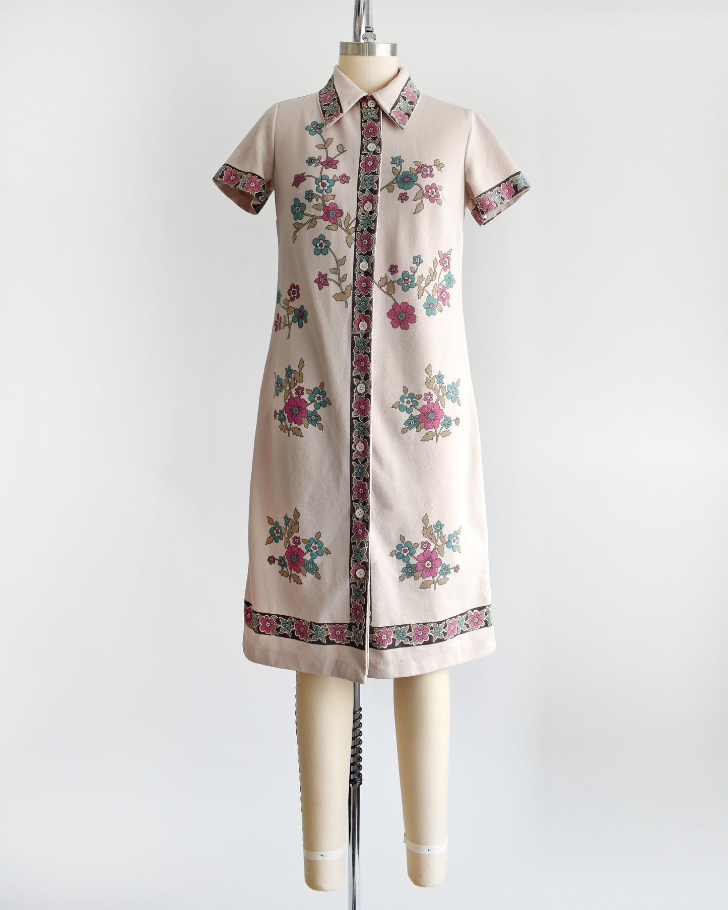 A vintage 1970s light brown mod dress with button front that features a blue and pink floral print 