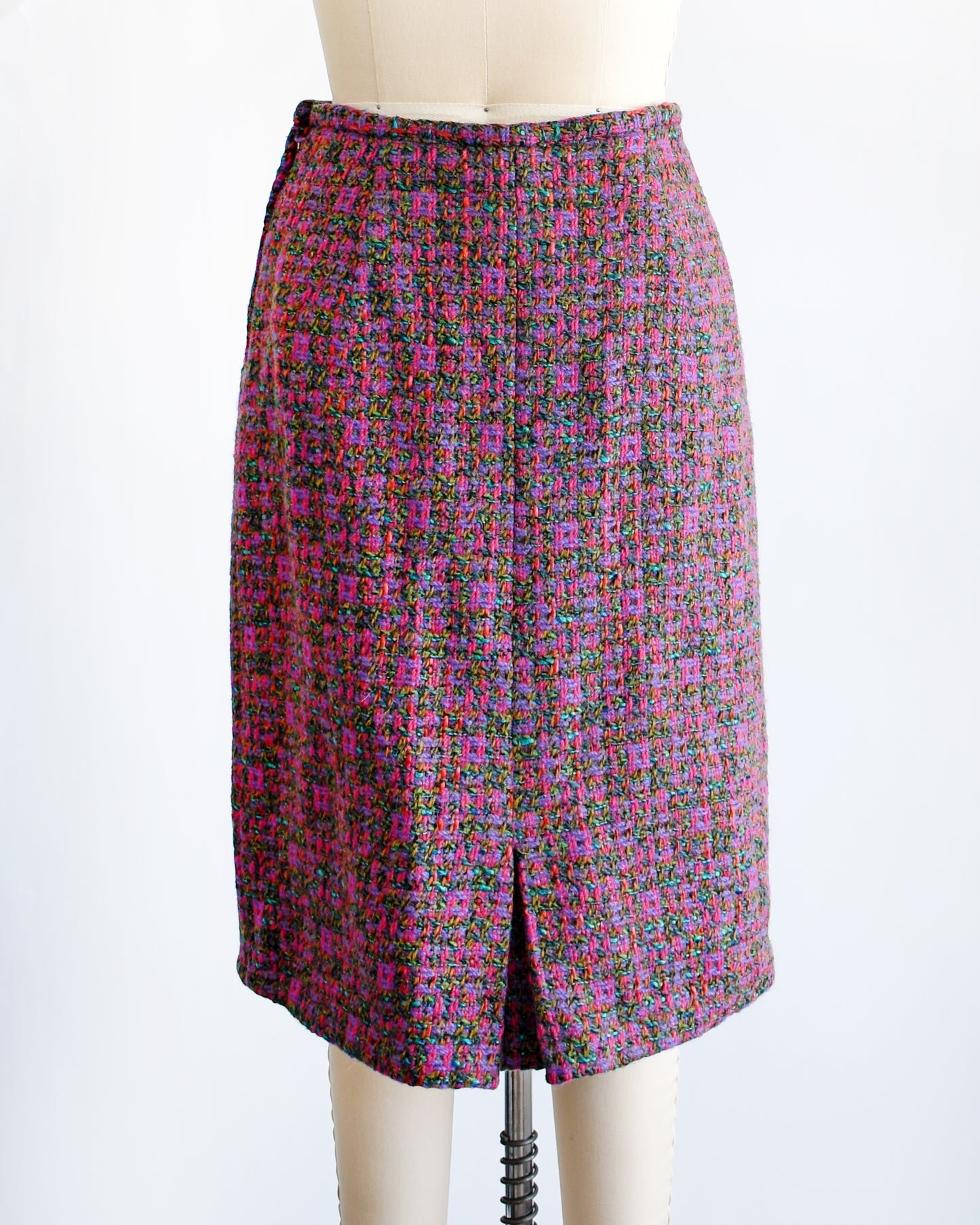 Back view of a This 1960s vintage tweed skirt showcases multi-colored woven wool, displaying a palette of bright pink, purple, teal, brown, green and red hues
