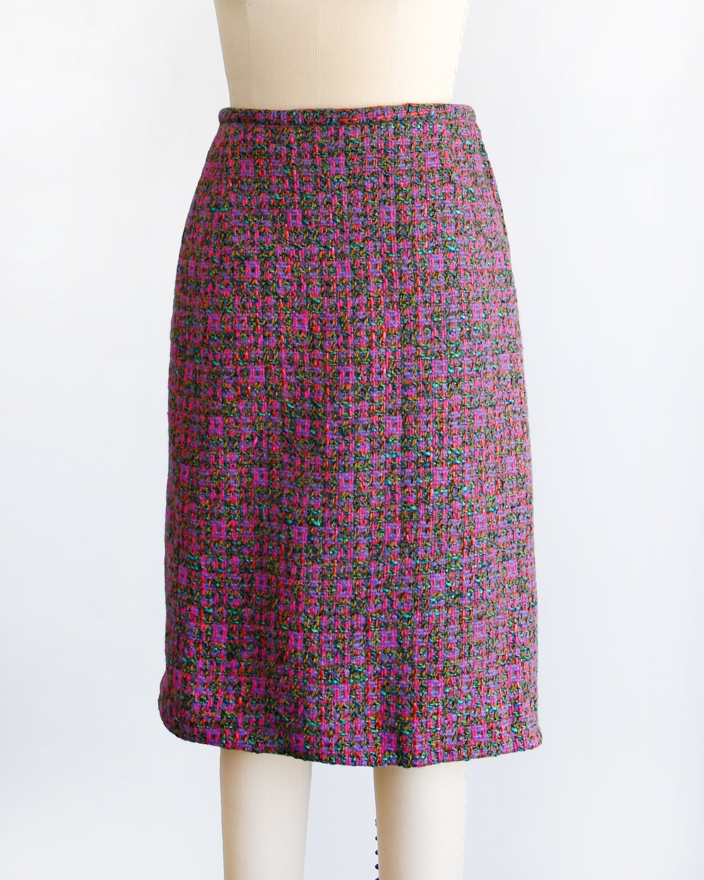Side front view of a 1960s vintage tweed skirt showcases multi-colored woven wool, displaying a palette of bright pink, purple, teal, brown, green and red hues