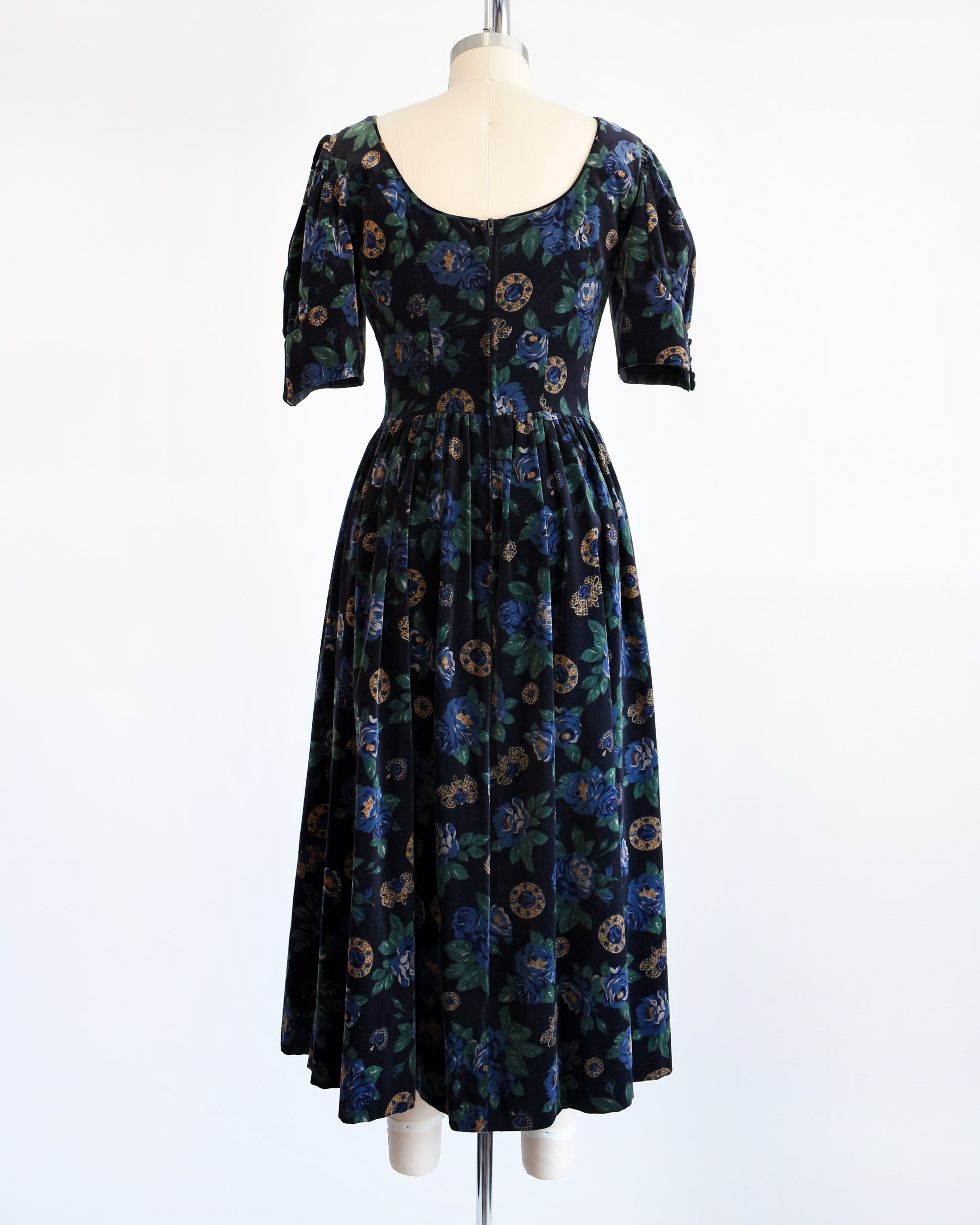 Back view of a vintage 1980s Laura Ashley dress. Black cotton velvet with a navy blue floral and metal gold jewels print.