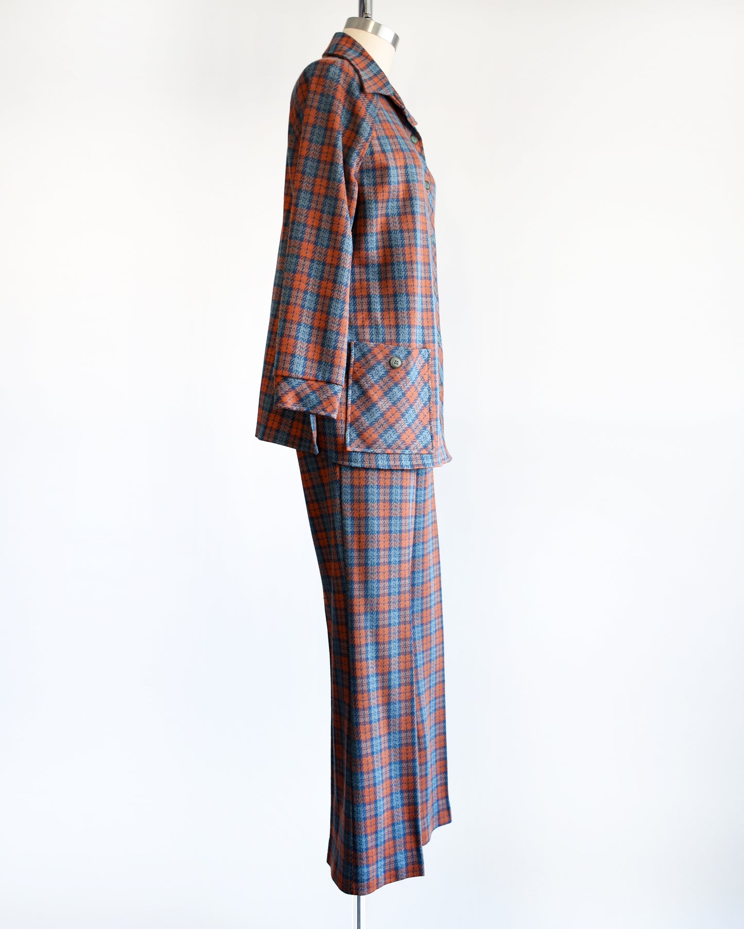 Side view of a vintage 1970s blue and orange plaid pantsuit. This set includes a blue and orange plaid long sleeve blouse and matching wide leg pants.