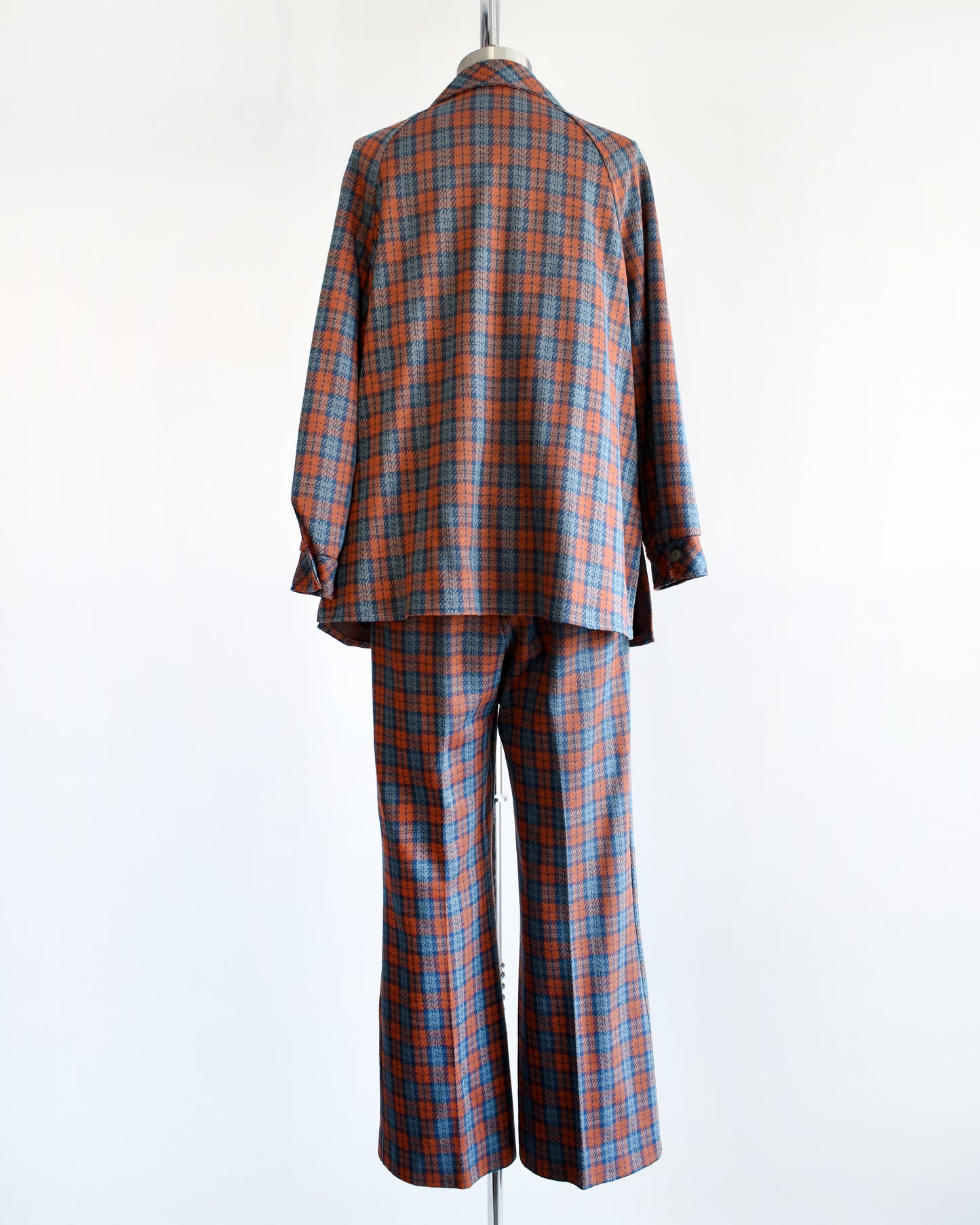 Back view of a vintage 1970s blue and orange plaid pantsuit. This set includes a blue and orange plaid long sleeve blouse and matching wide leg pants.