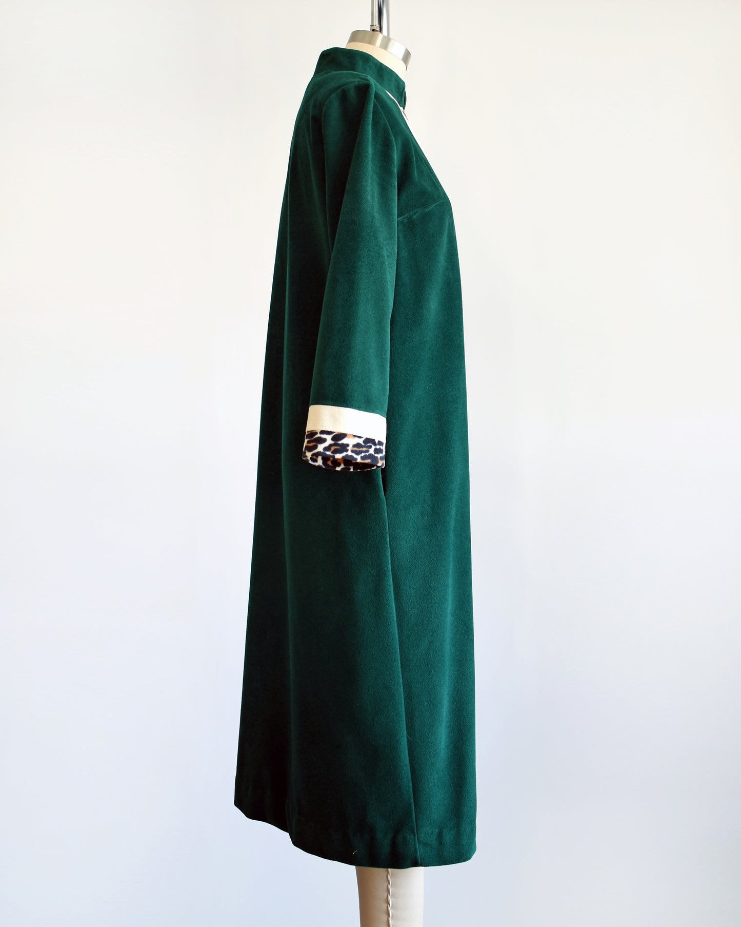 Side view of a vintage 1970s robe by Vanity Fair that is a rich dark green with a white and leopard print stripe going down the front and matching stripes on the cuffs.