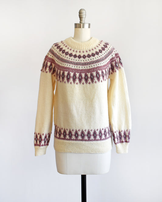 A vintage 1980s Dale of Norway cream wool sweater that has a purple Fair Isle pattern around the collar that's accented with matching purple nubby details.