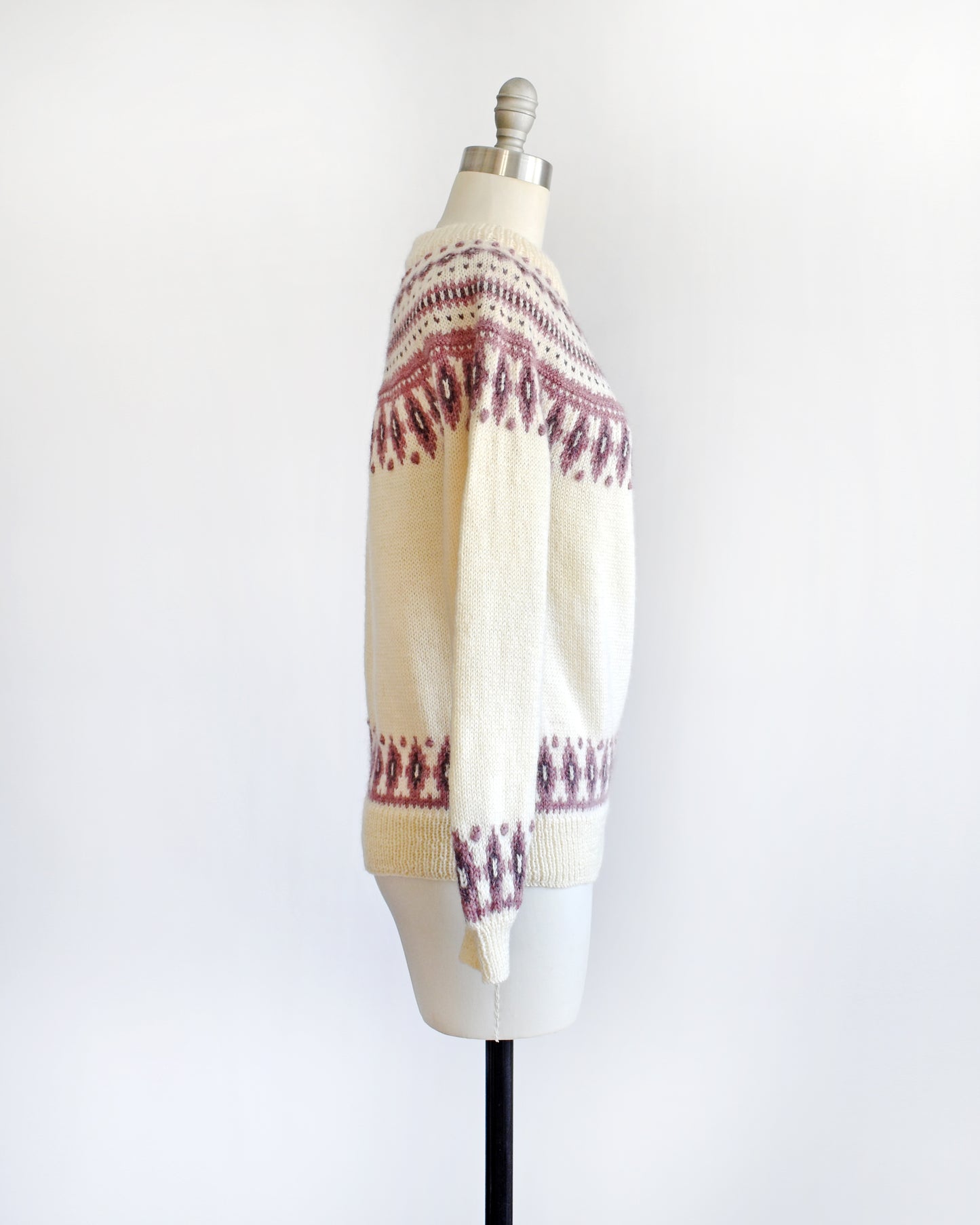 Side view of a vintage 1980s Dale of Norway cream wool sweater that has a purple Fair Isle pattern around the collar that's accented with matching purple nubby details.