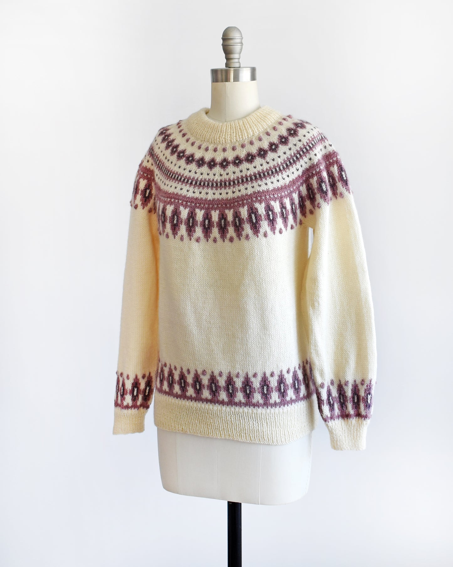 Side view of a vintage 1980s Dale of Norway cream wool sweater that has a purple Fair Isle pattern around the collar that's accented with matching purple nubby details.