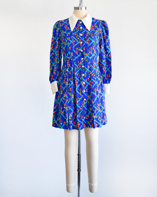 A vintage 1970s blue floral mini dress that has a white collar with matching cuffs, and white buttons down the front.
