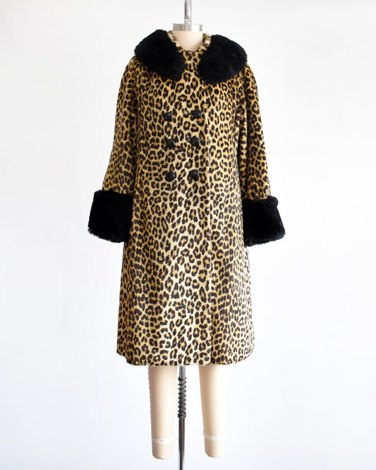 A vintage 1960s faux fur leopard print coat. Black plush trim along the collar and on the cuffs. The coat is buttoned all the way up.