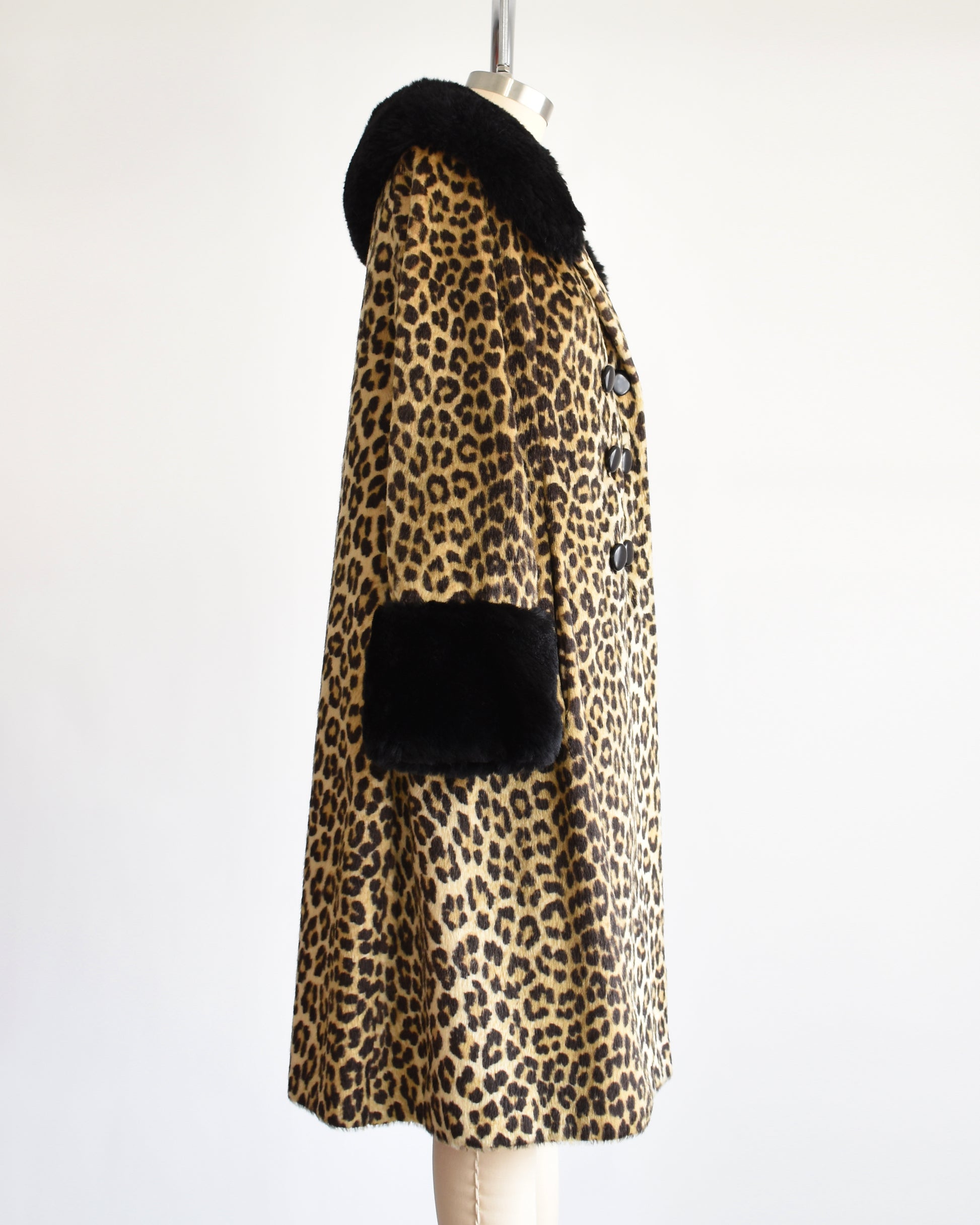 Side view of a vintage 1960s faux fur leopard print coat. Black plush trim along the collar and on the cuffs.