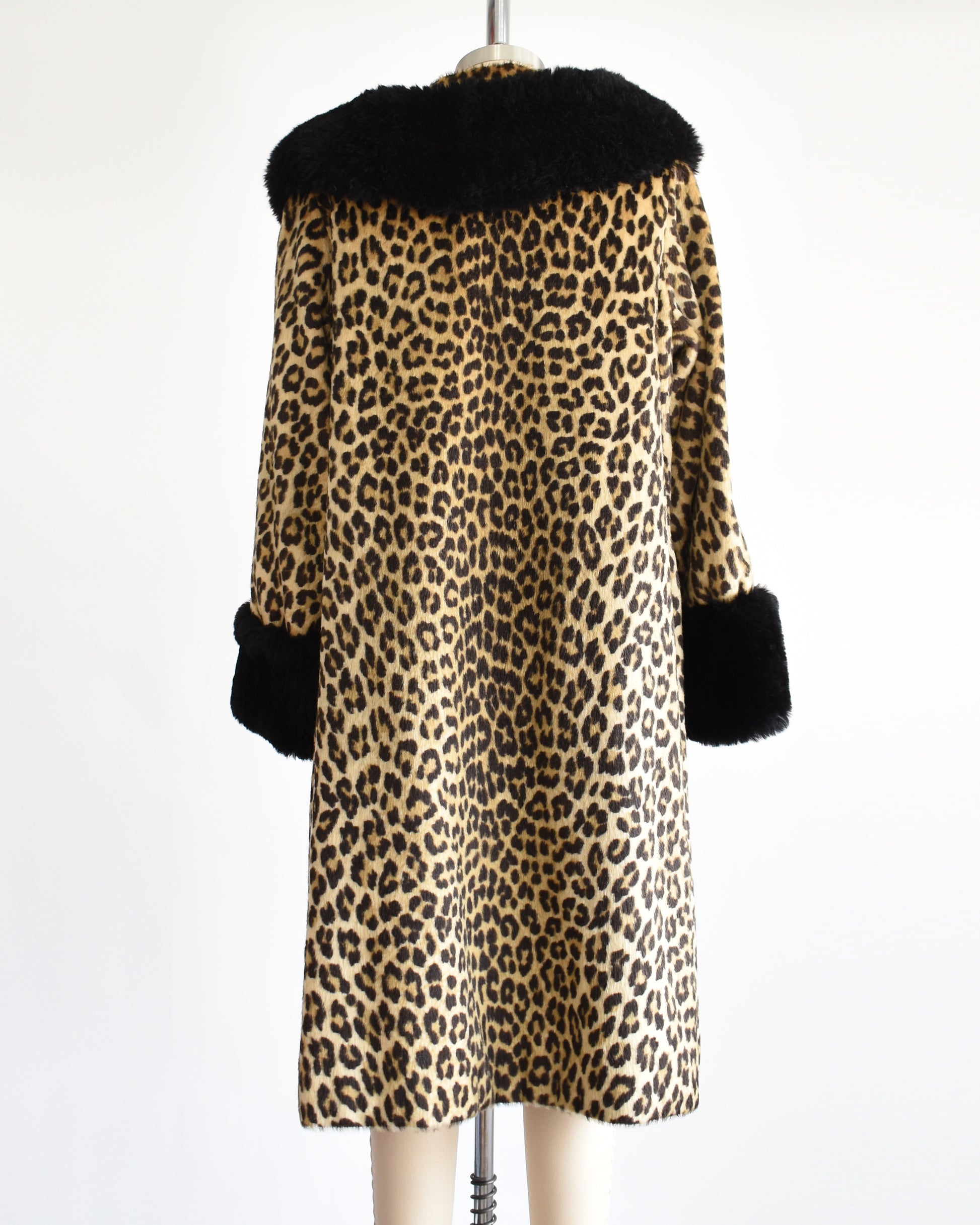 Back view of a vintage 1960s faux fur leopard print coat. Black plush trim along the collar and on the cuffs.