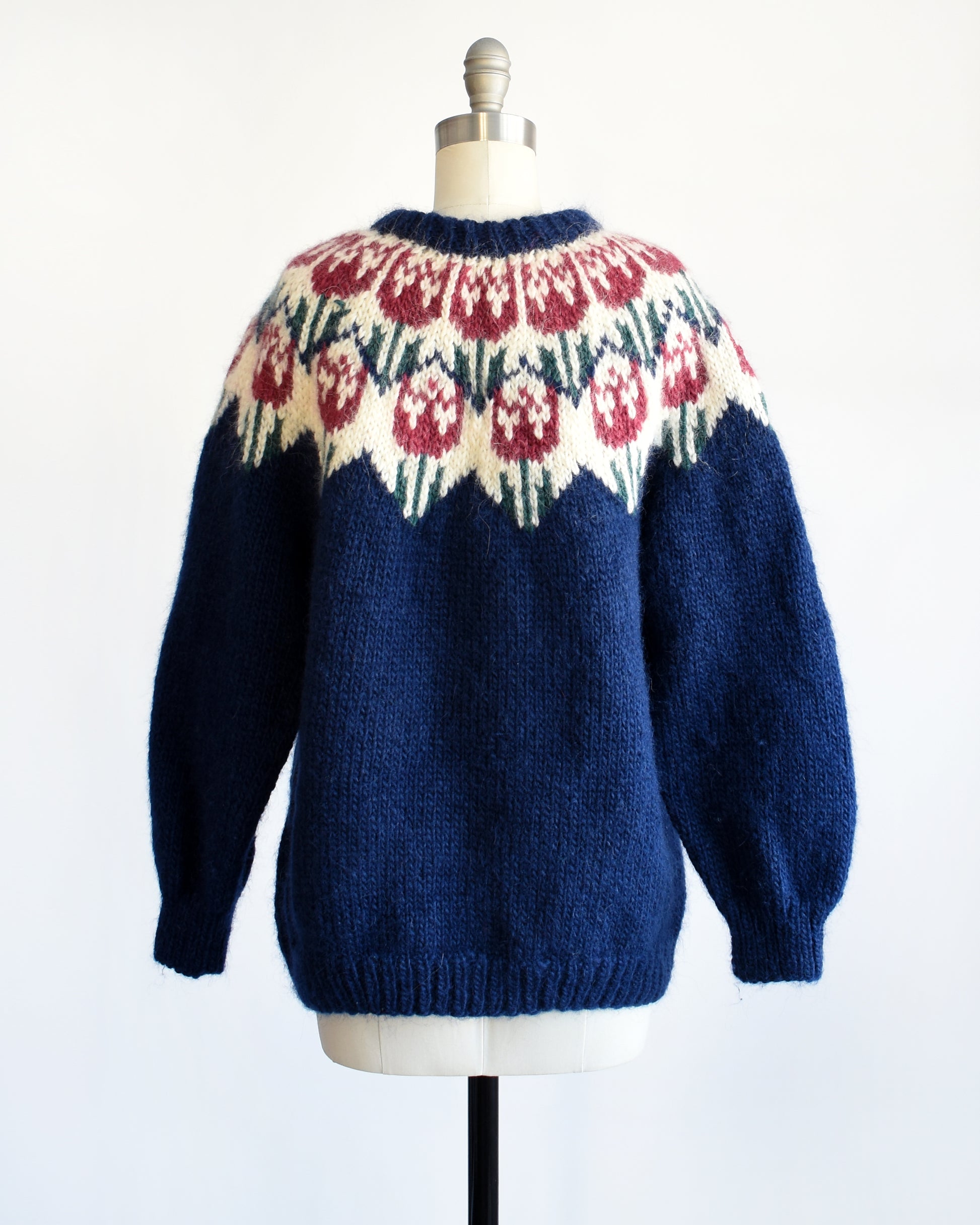 Back view of a a vintage 1980s navy blue Fair Isle sweater that features a dark pink and green tulip pattern around the collar.