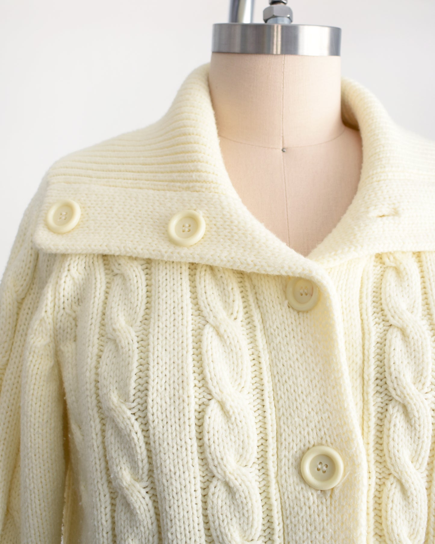close up of the collar on a vintage 1970s cream cable knit cardigan