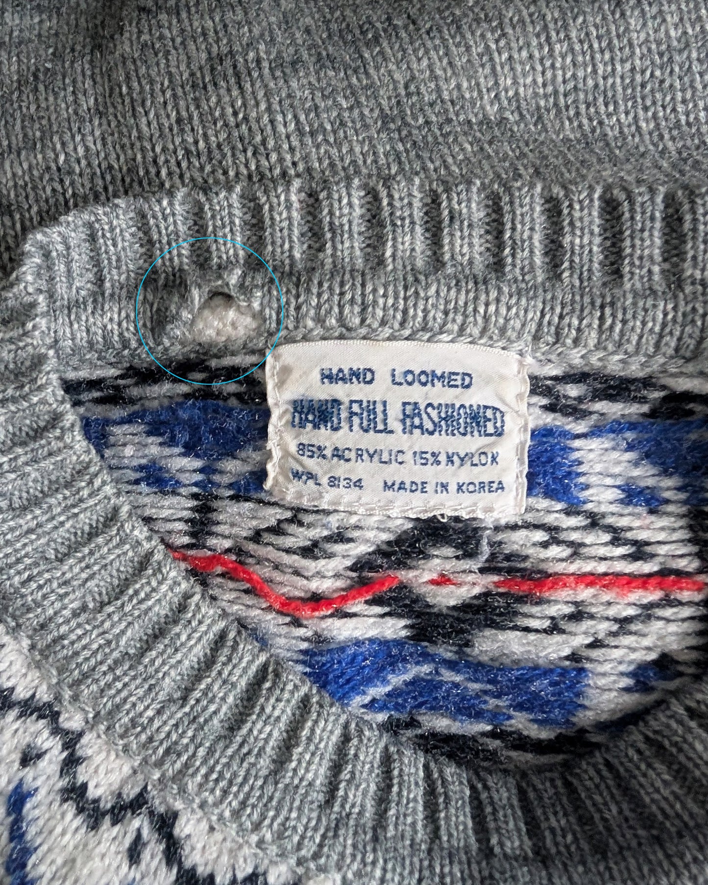 Gray sweater with a label indicating 'Hand Loomed' and 'Made in Korea'.