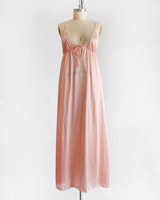 A vintage 1970s peachy pink nightgown that has lace trim on the bodice