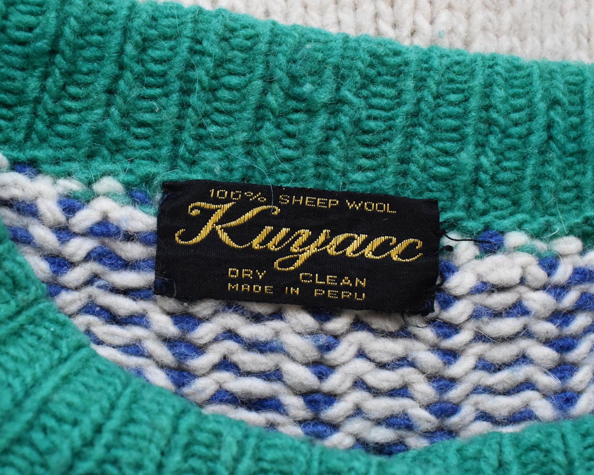 Close up of the tag that says 100% sheep wool, Kuyacc, Dry Clean, Made in Peru