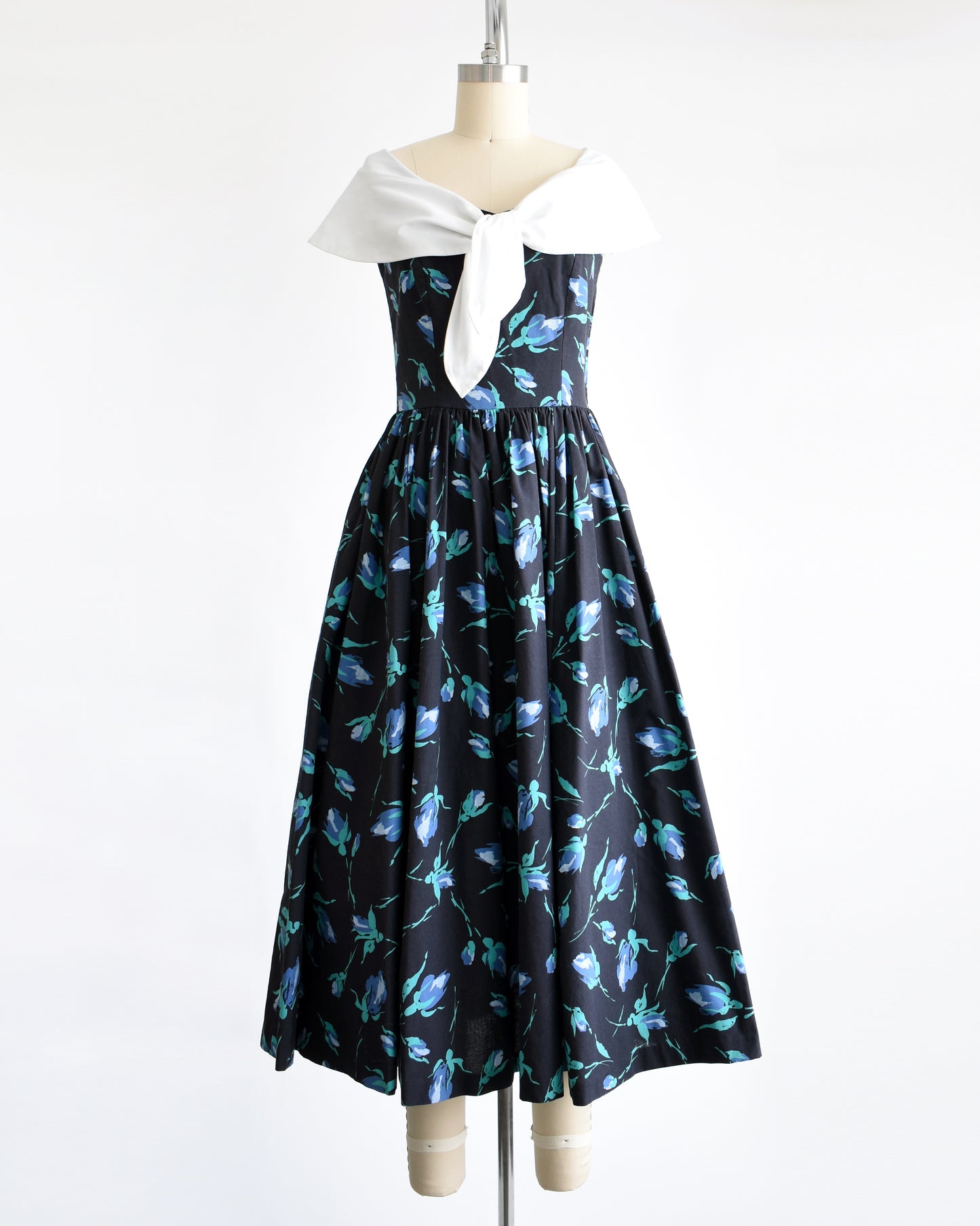 a vintage 1980s Laura Ashley dress that has a black and blue floral pattern and large white shawl collar.