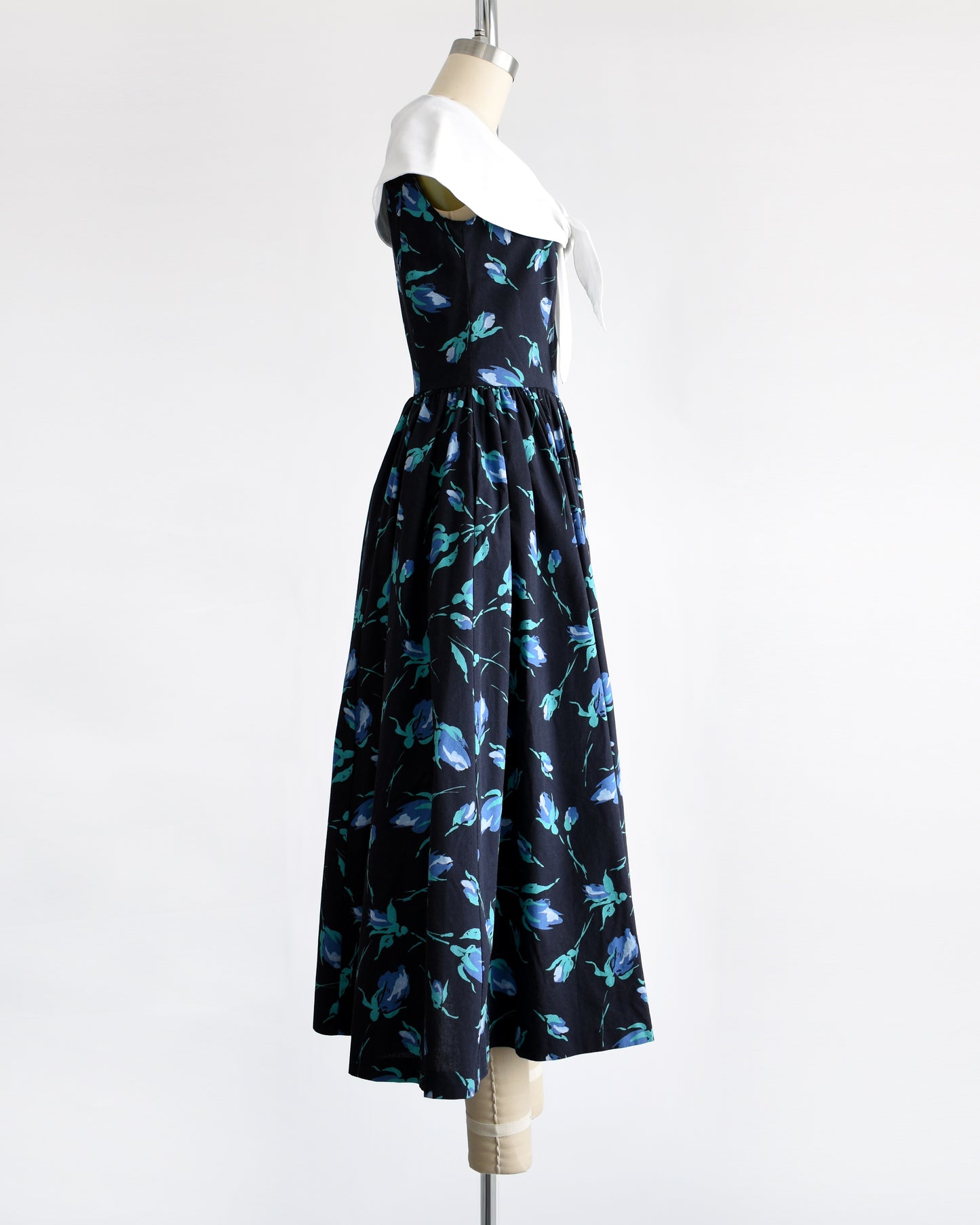 side view of a vintage 1980s Laura Ashley dress that has a black and blue floral pattern and large white shawl collar.