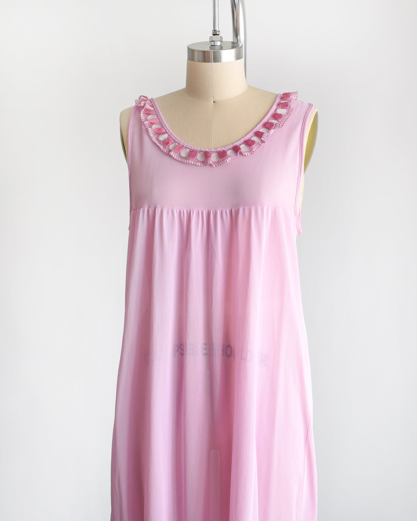 Side front view of a vintage late 1960s early 1970s pinky purple nightgown with embroidered ruffle trim under the neckline