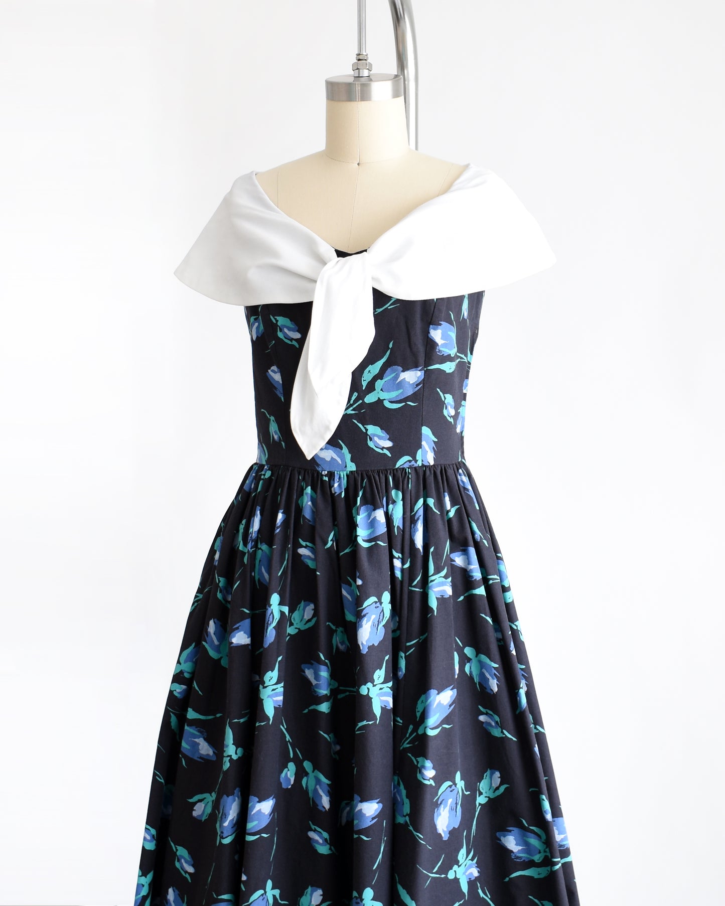 side front view of a vintage 1980s Laura Ashley dress that has a black and blue floral pattern and large white shawl collar.