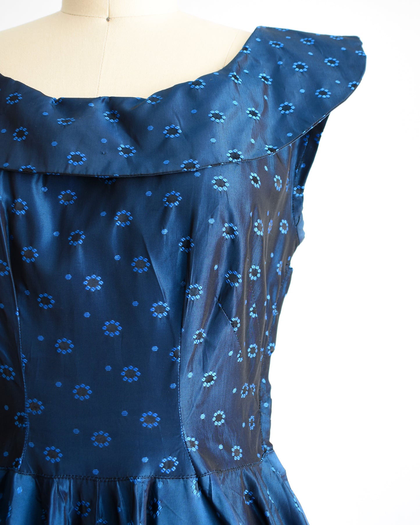 close up of the bodice of a vintage 1950s blue black floral brocade dress
