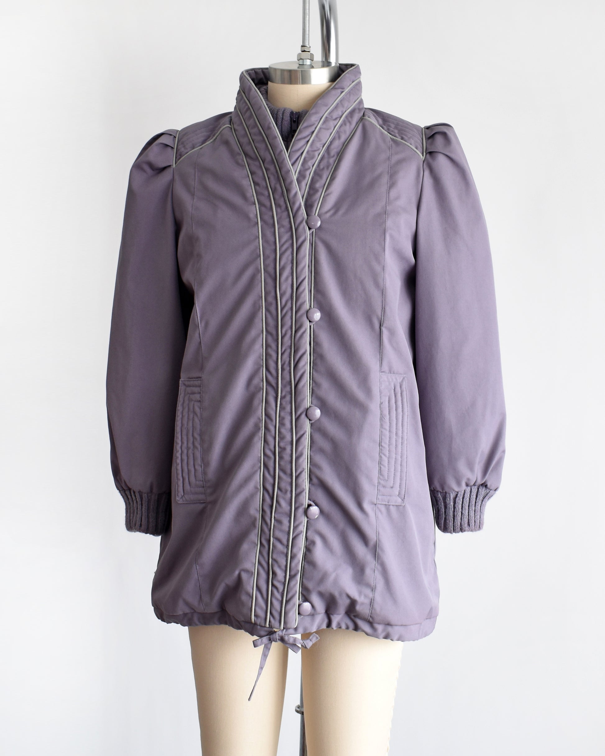 Side front view of a vintage 1980s purple puffy coat with shawl style collar with gray trim