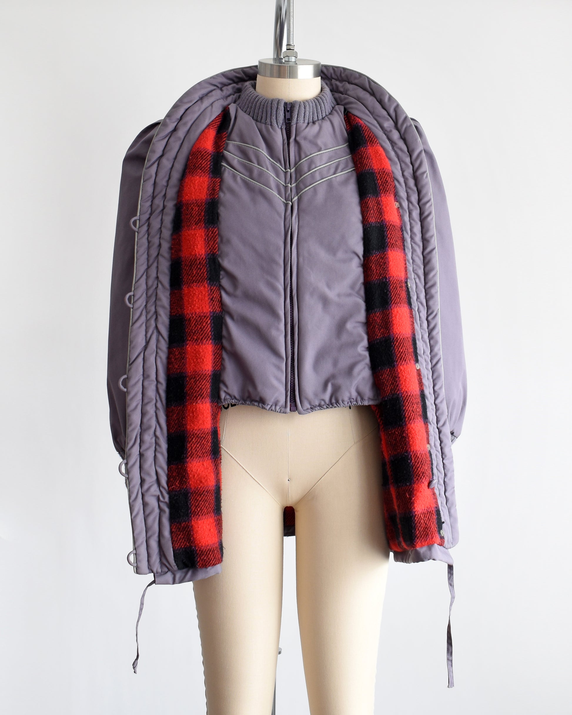  a vintage 1980s purple puffy coat with shawl style collar with gray trim. The coat is opened showing the plaid lining and built in vest
