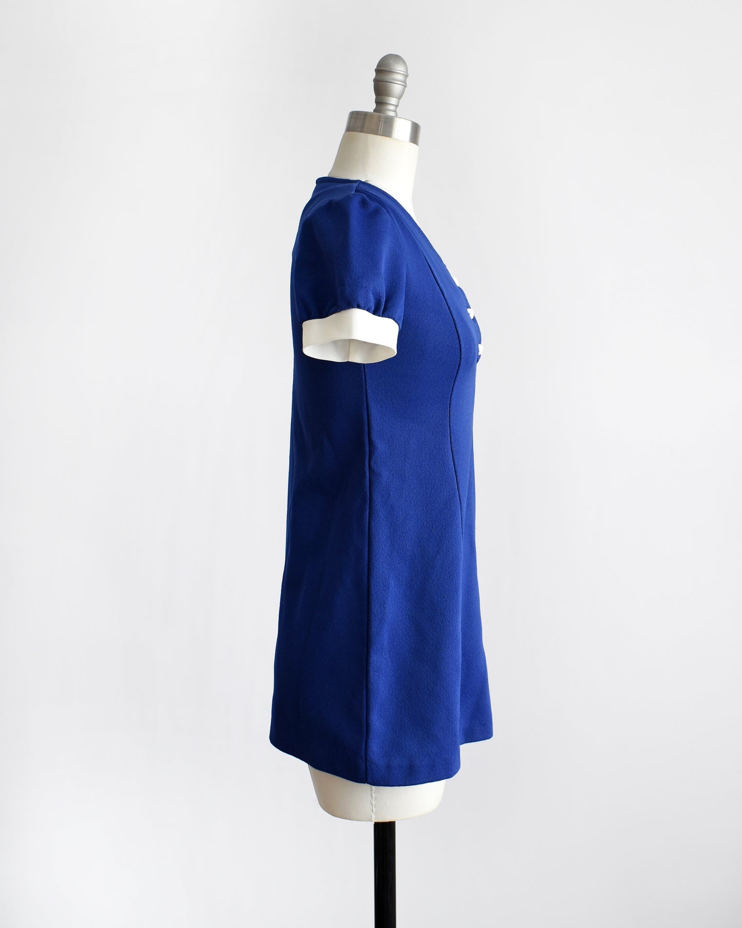 side view of a vintage late 1960s early 1970s dark blue top with three white heart buttons under the neckline. 