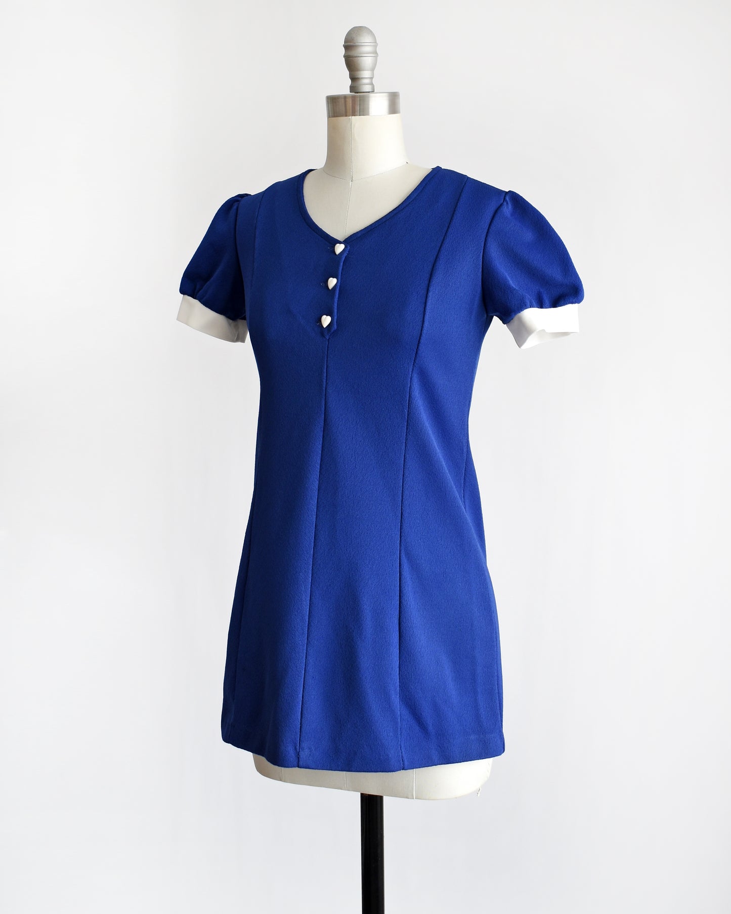 side front view of a vintage late 1960s early 1970s dark blue top with three white heart buttons under the neckline.