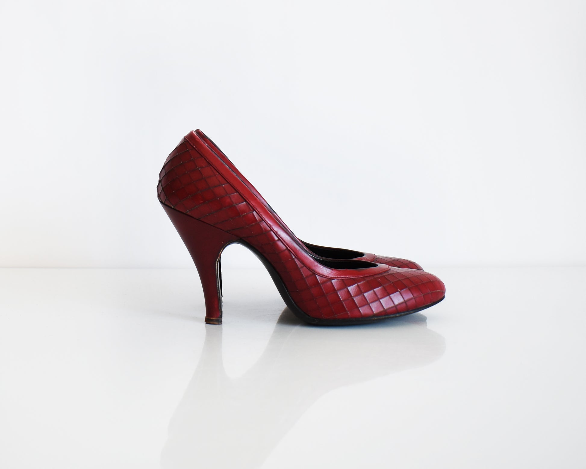 side view of a pair of vintage 1960s burgundy criss-cross pattern high heels