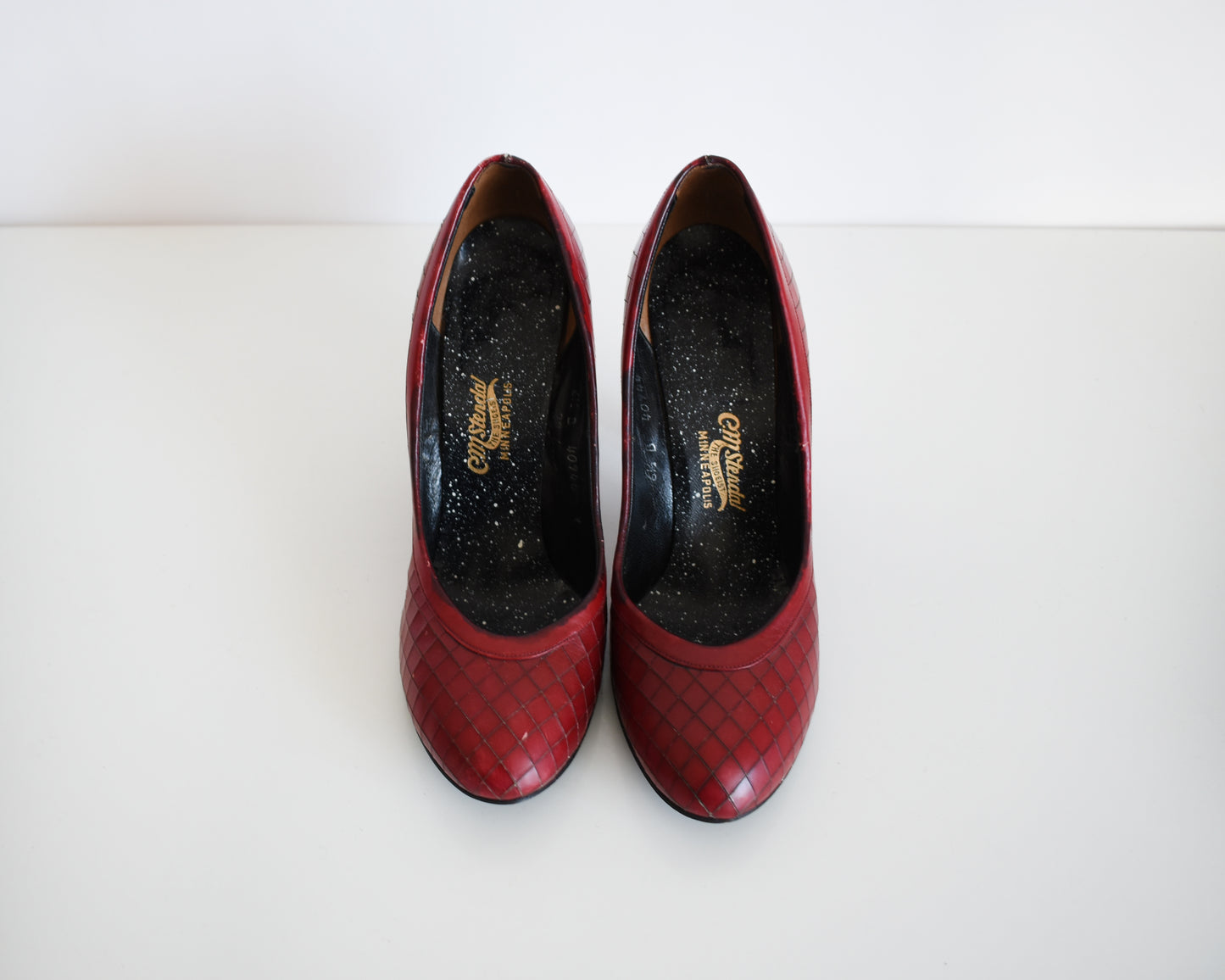 front view of a pair of vintage 1960s burgundy criss-cross pattern high heels