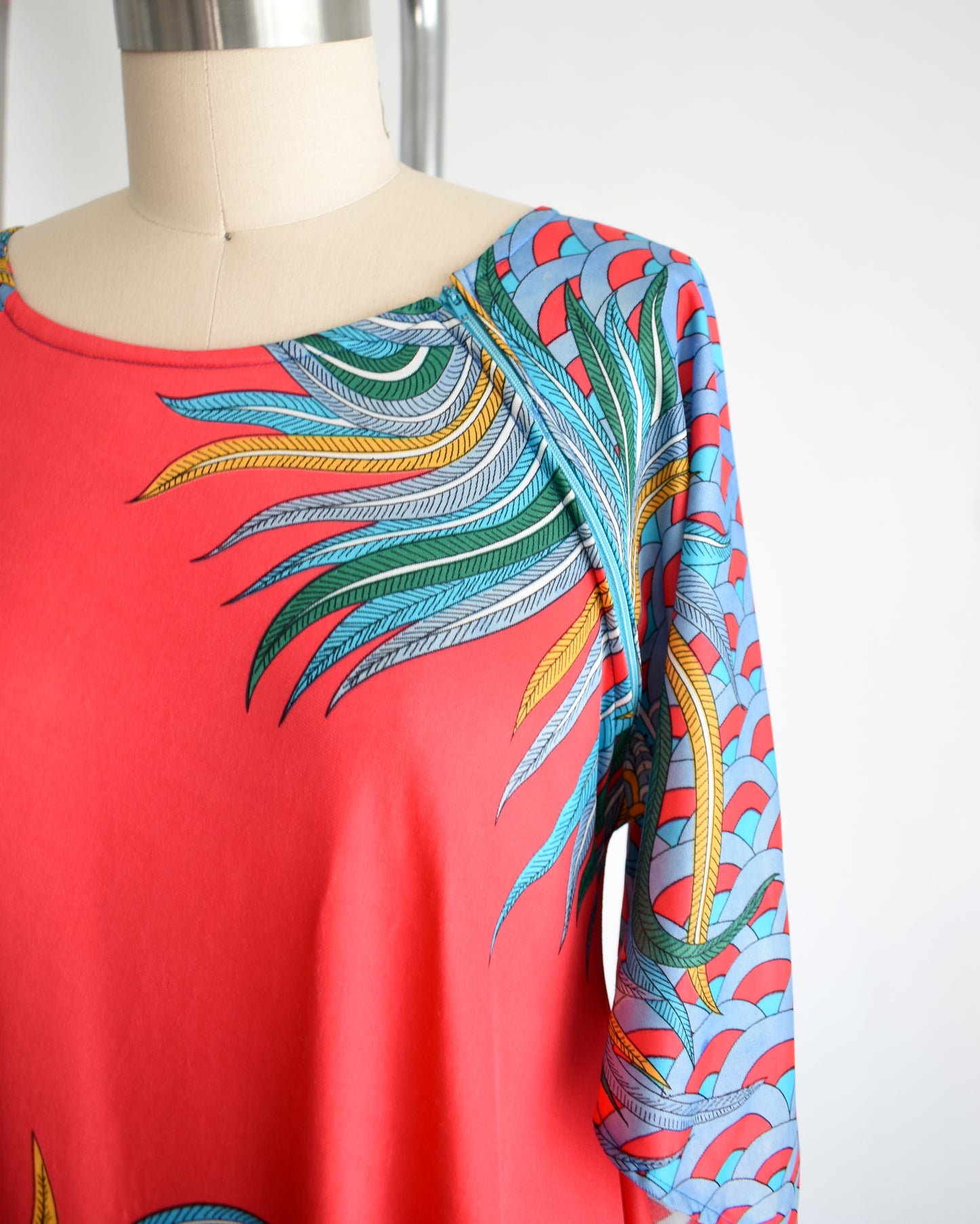 side front view of a vintage 1970s red and blue psychedelic bird caftan, which shows the shoulder zipper