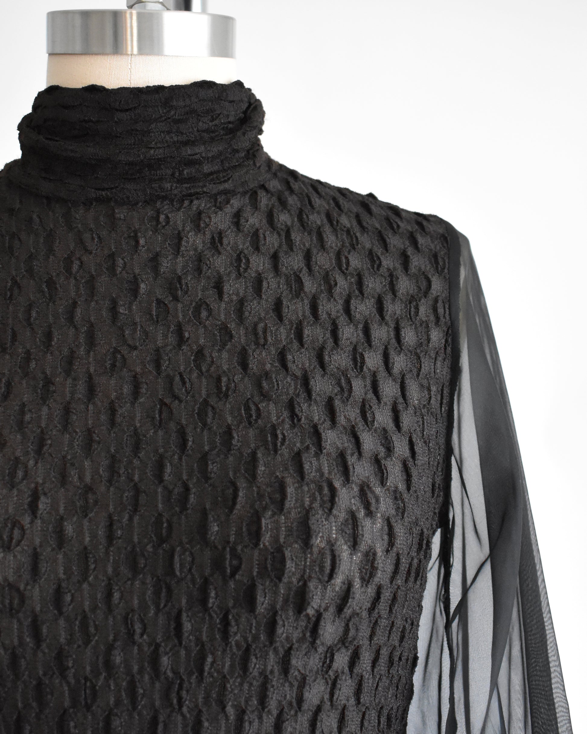 close up of the bodice of a vintage 1970s black textured bodysuit with long sleeves
