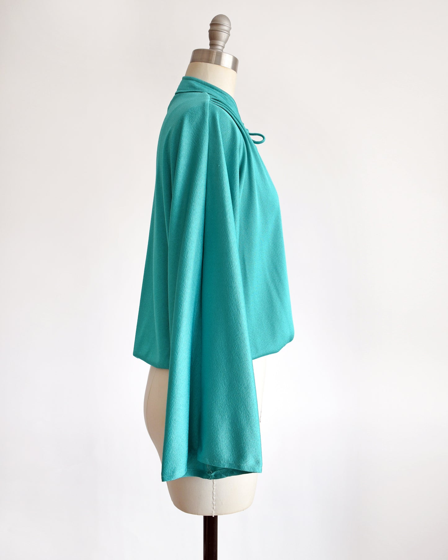 side view of a vintage 1970s teal bell sleeve blouse