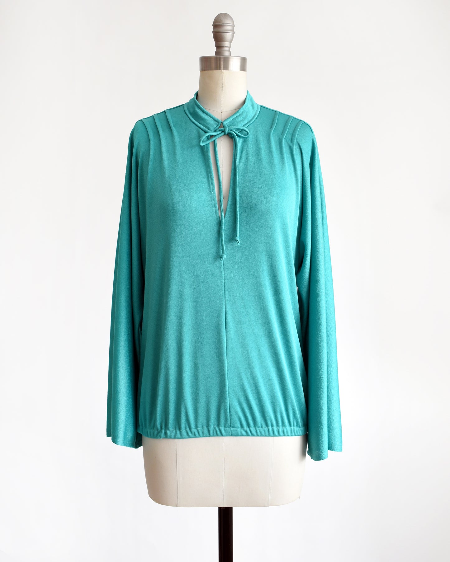 a vintage 1970s teal bell sleeve blouse