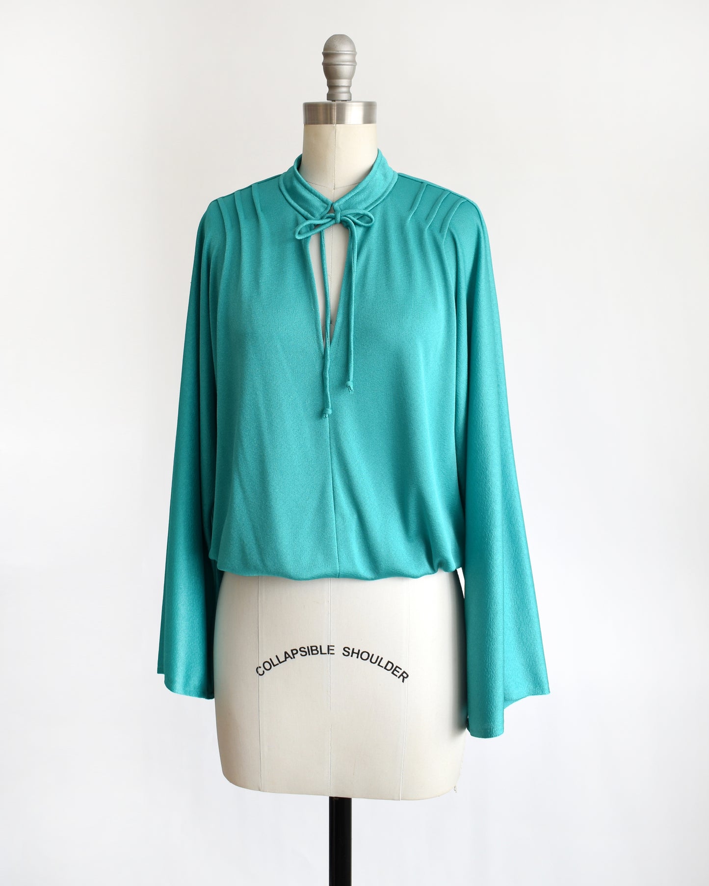 side front view of a vintage 1970s teal bell sleeve blouse