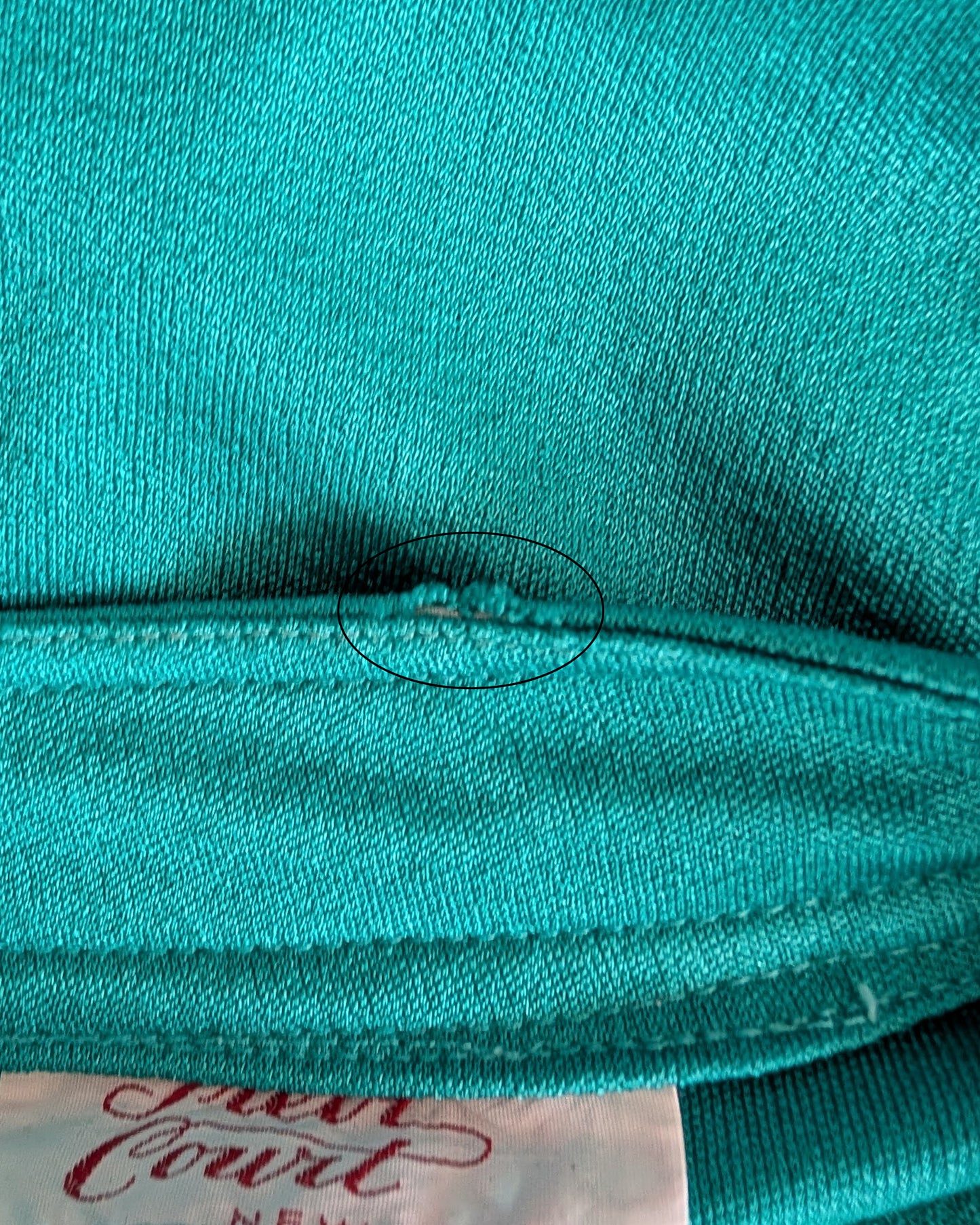 close up of the small fray on a vintage 1970s teal bell sleeve blouse