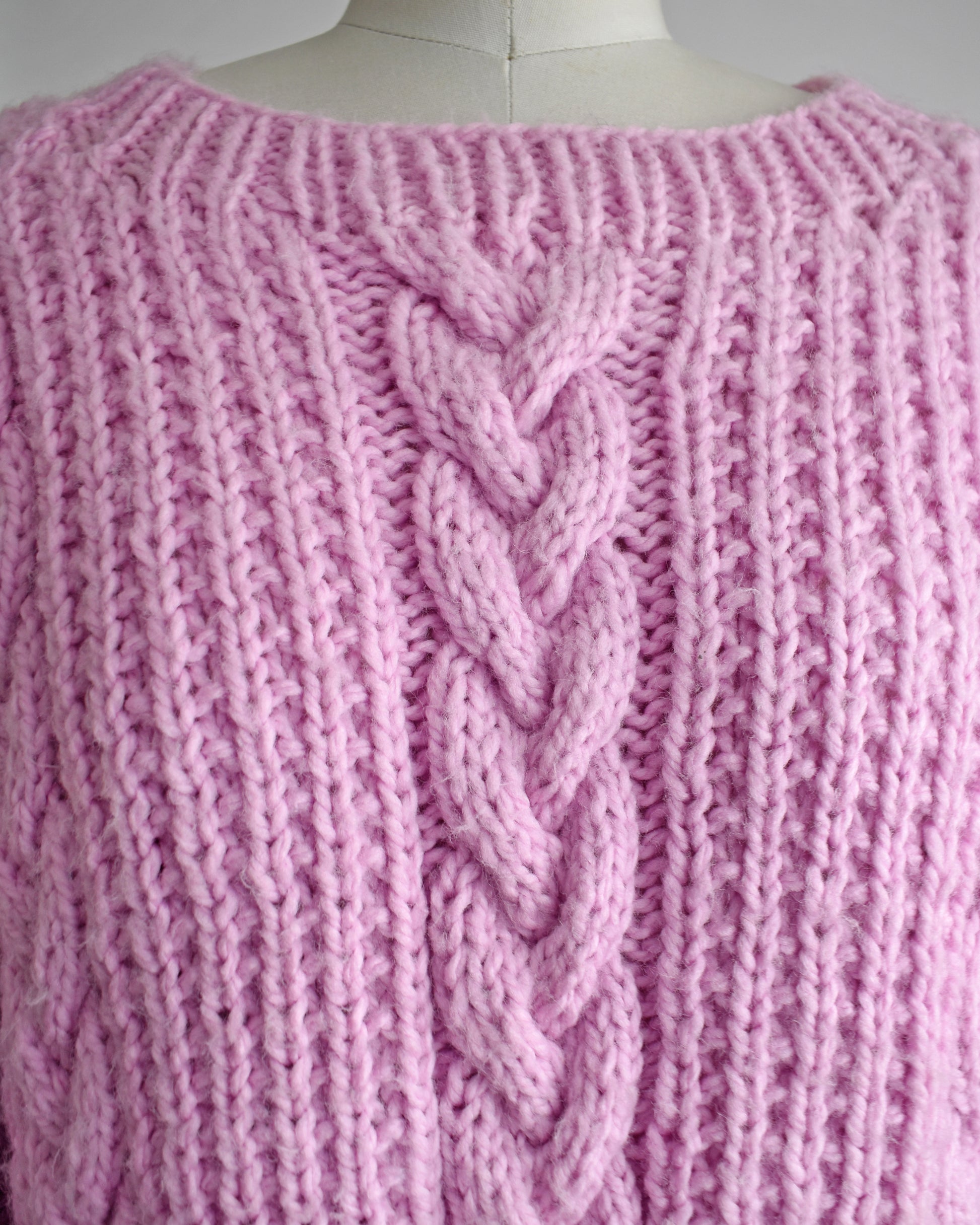 close up of a vintage 1980s chunky purple pink cable knit sweater