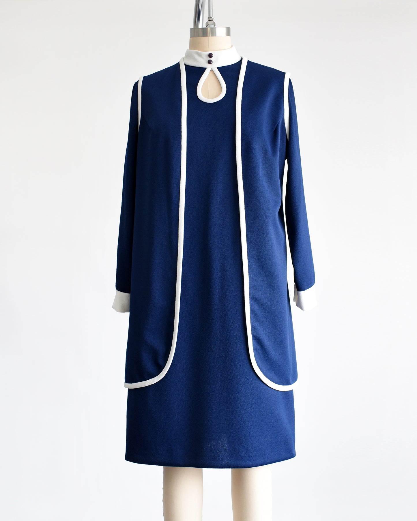 This late 1960s to early 1970s mod two piece set features a navy blue long sleeve dress and matching vest.  There is no belt in this photo