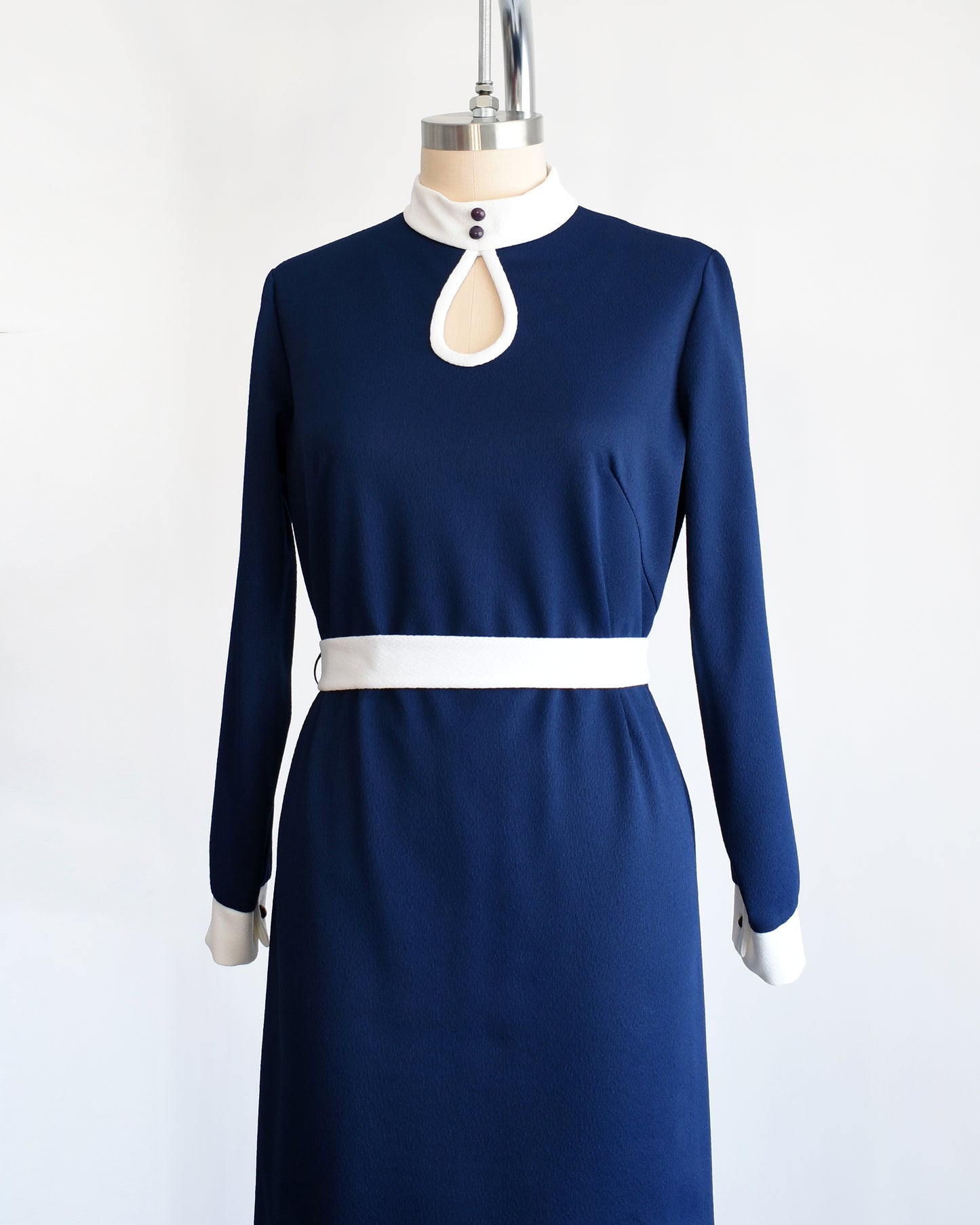 Side front view of a late 1960s to early 1970s navy and white mod dress with white belt