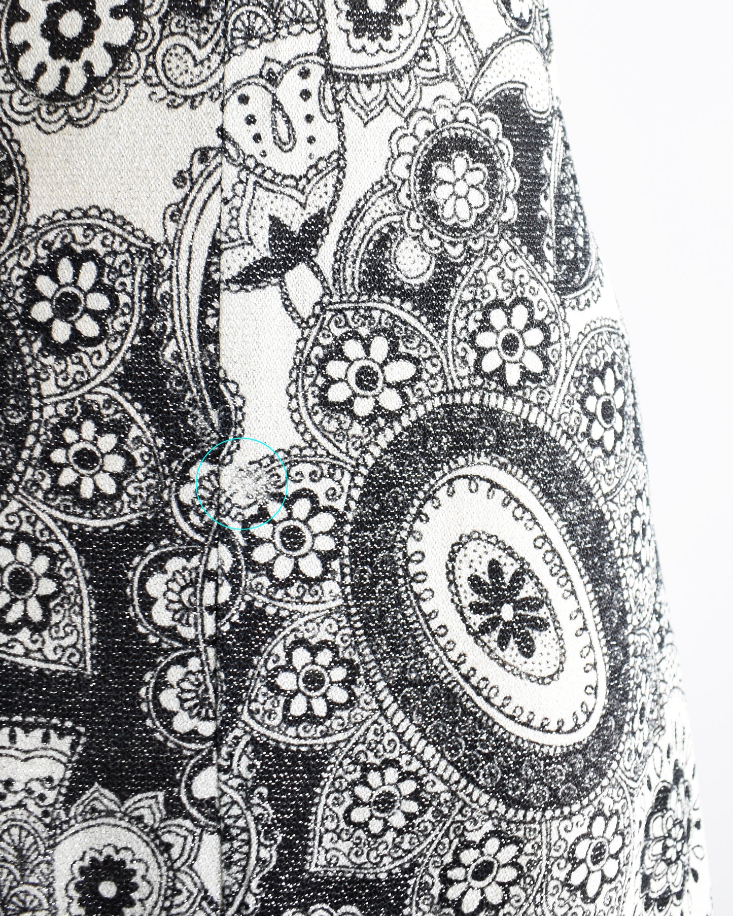 Close up of the skirt which shows the mod floral paisley print with metallic threads.