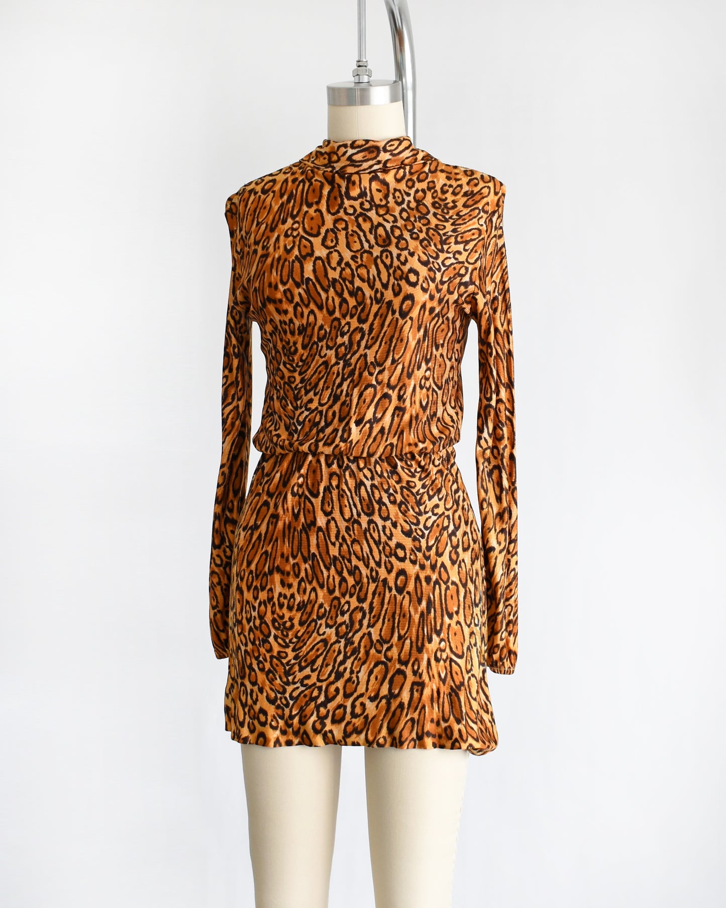 side front view of side by side view of a vintage 1960s leopard print mini dress. the dress is pulled up via the elastic waist