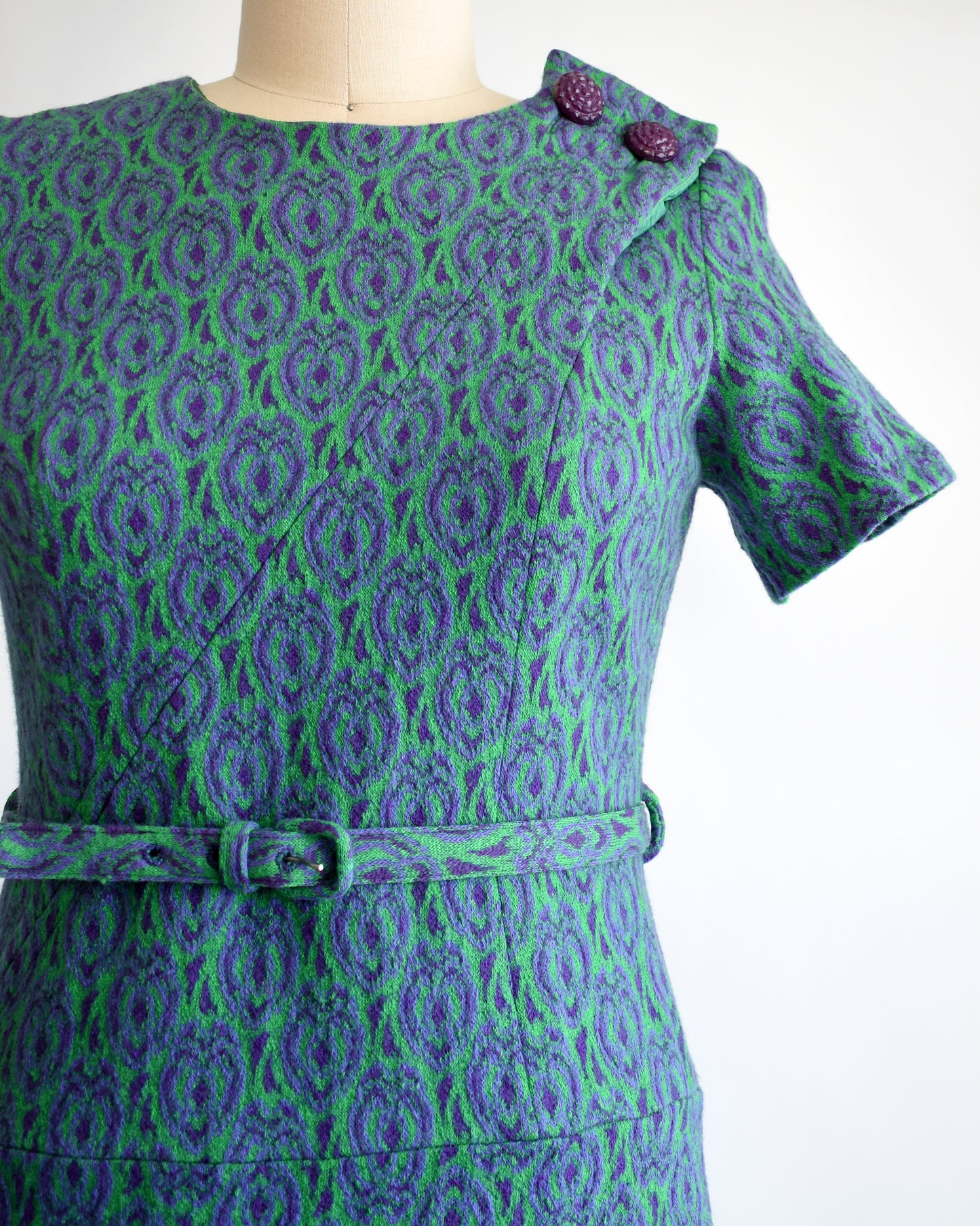 Close up of a vintage 1960s green and purple drop waist dress and matching belt