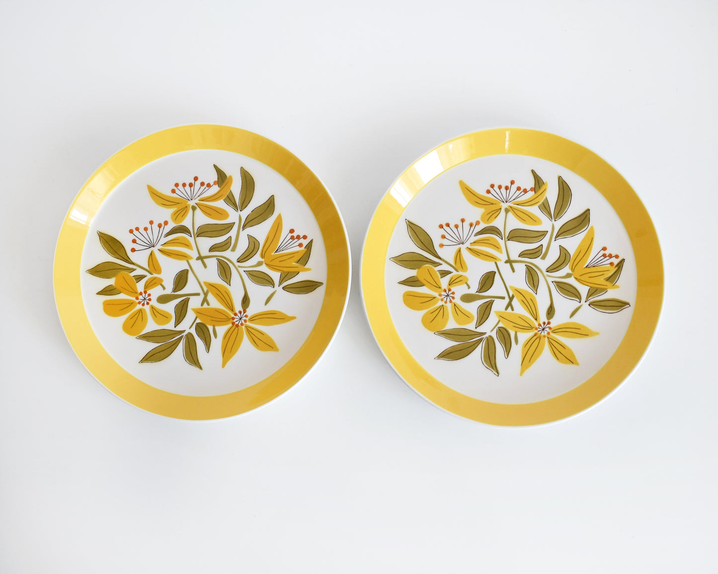 Two vintage 1970s plates from Mikasa Duplex line “Sunny Glow” D3504 pattern, designed by Ben Seibel. The plates have a wide yellow brim with a yellow, green, and orange floral motif at the center.