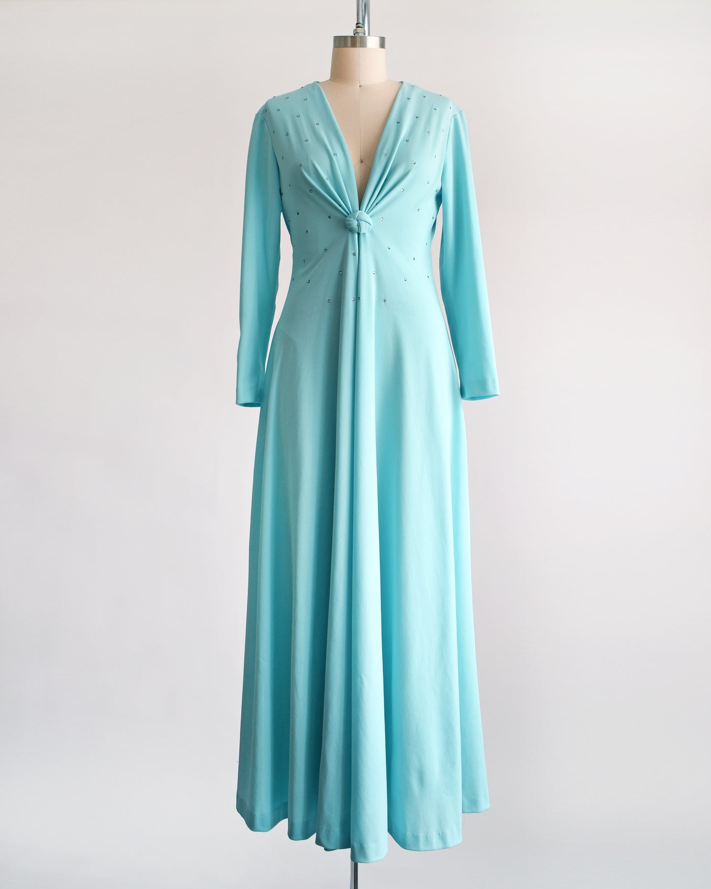 a vintage 1970s light blue maxi dress that has rhinestones on the bodice, a plunging v-neckline, and long sleeves